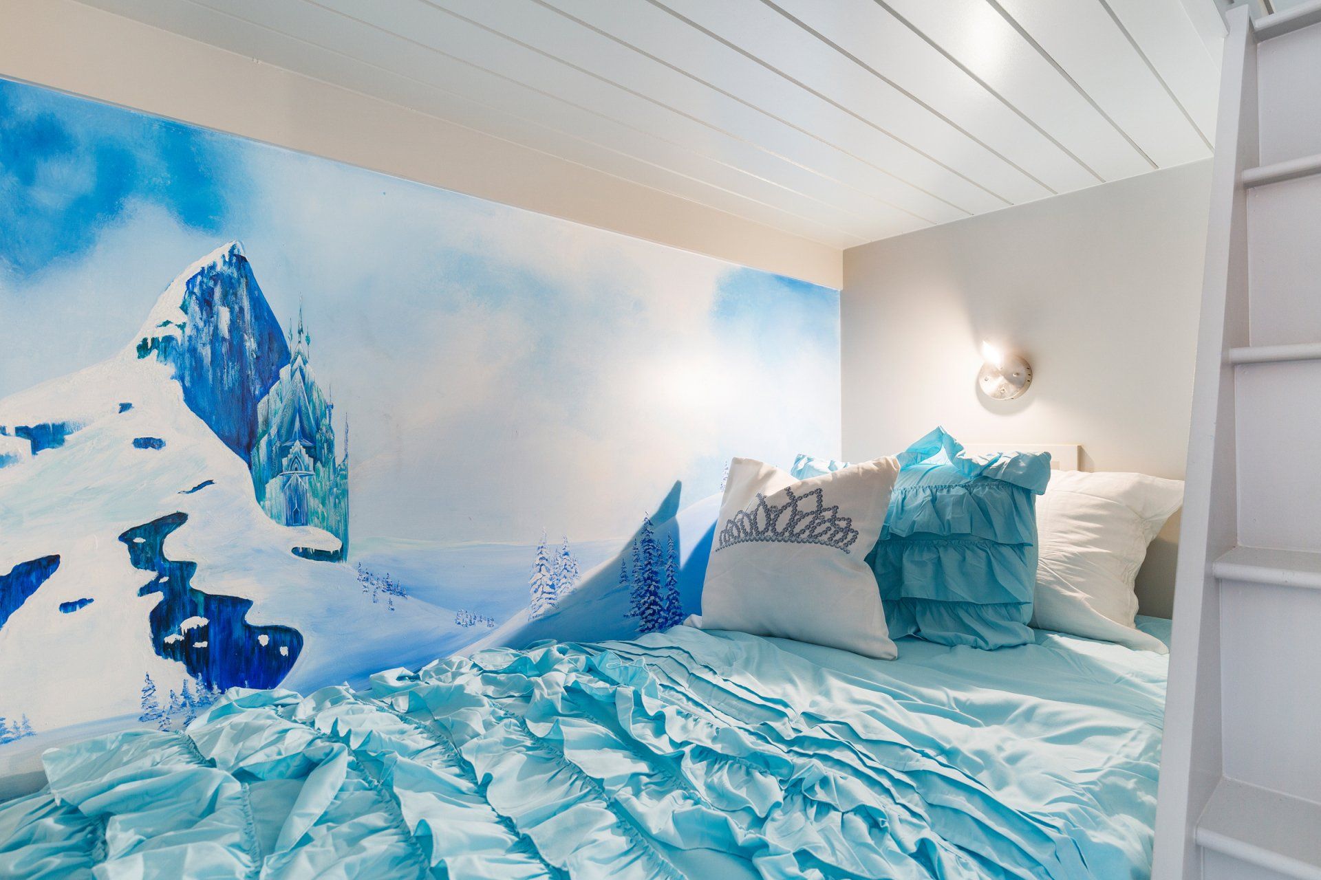 a bed with blue sheets and pillows in a bedroom with a frozen theme