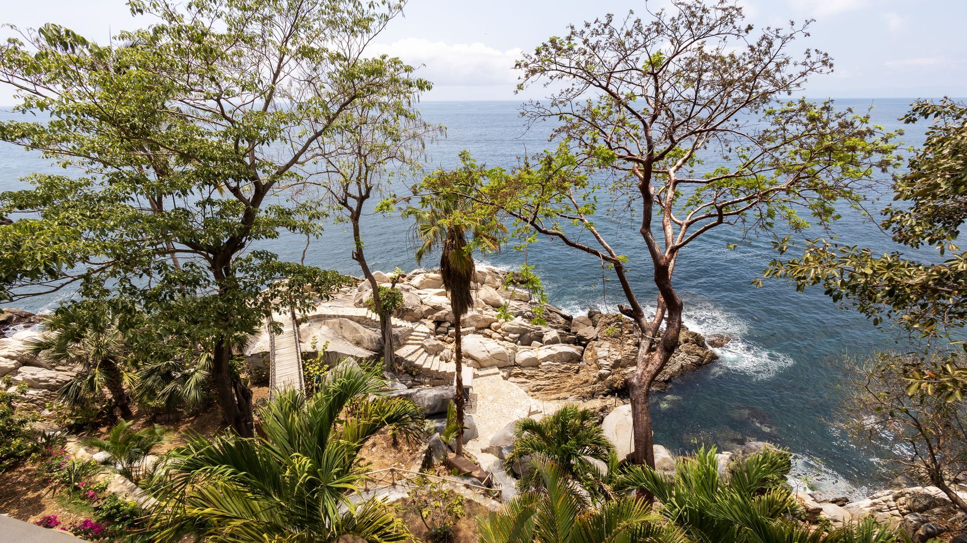 a view of a cliff overlooking the ocean with trees in the foreground