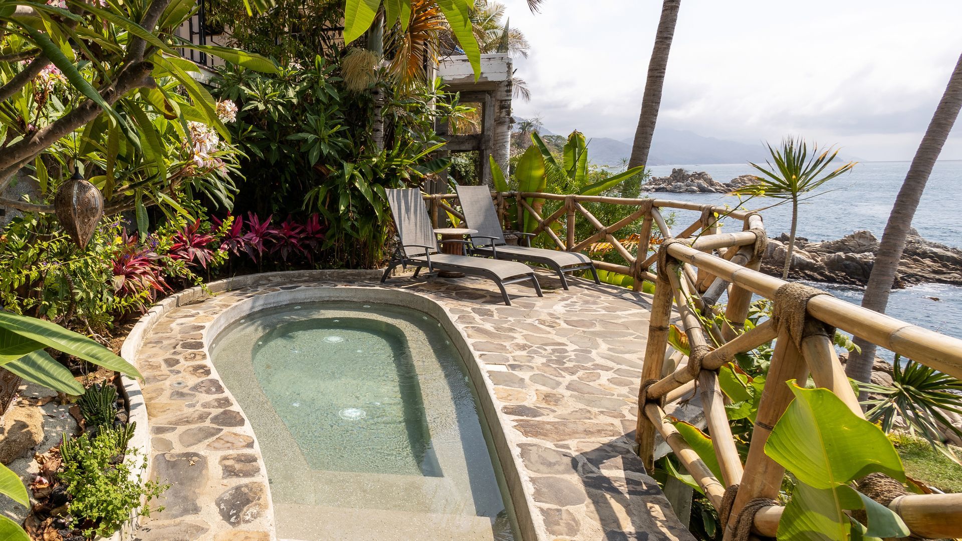 a small swimming pool is surrounded by a wooden fence next to the ocean