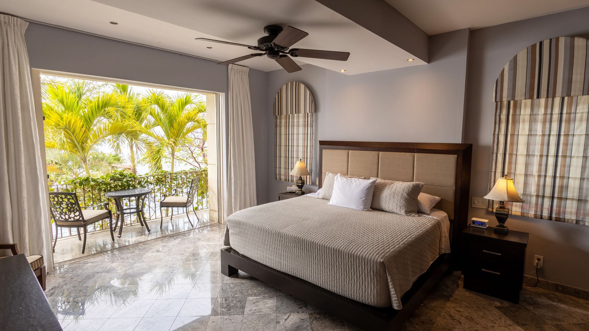 a hotel room with a king size bed and a ceiling fan