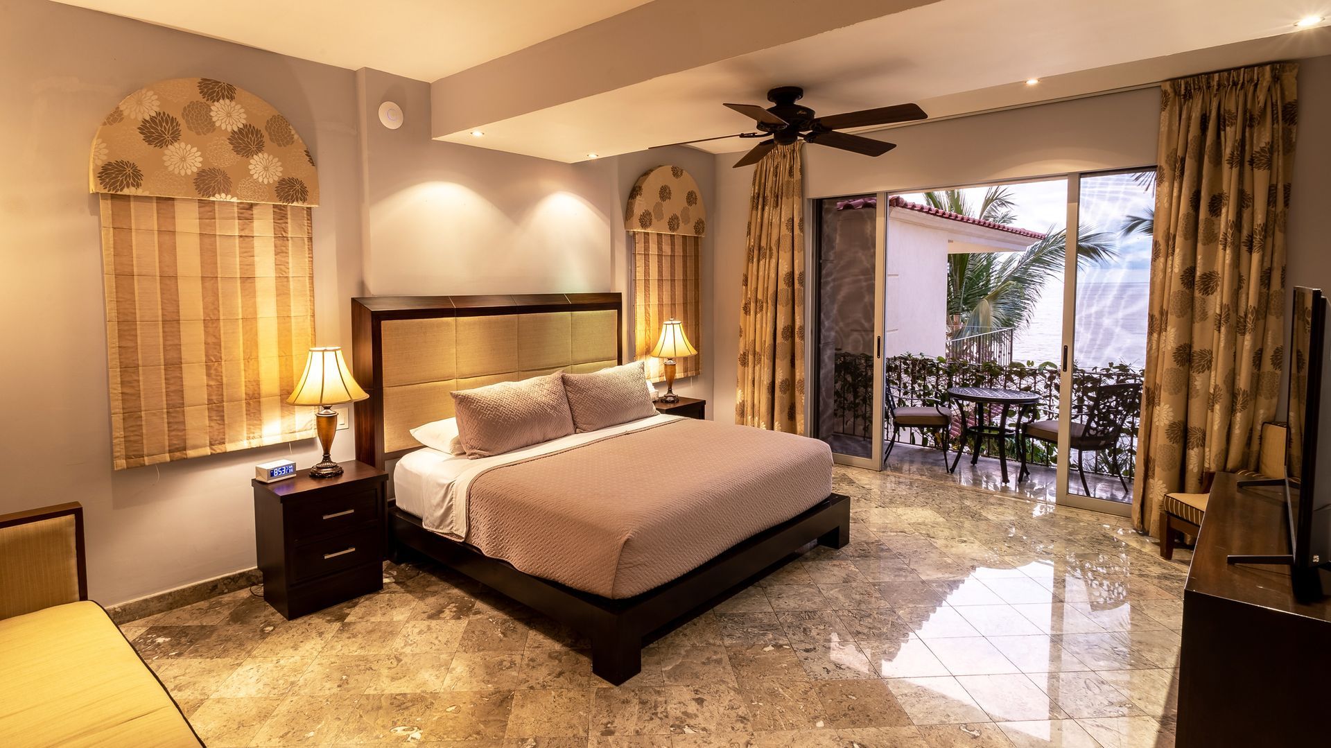 a hotel room with a king size bed and a ceiling fan