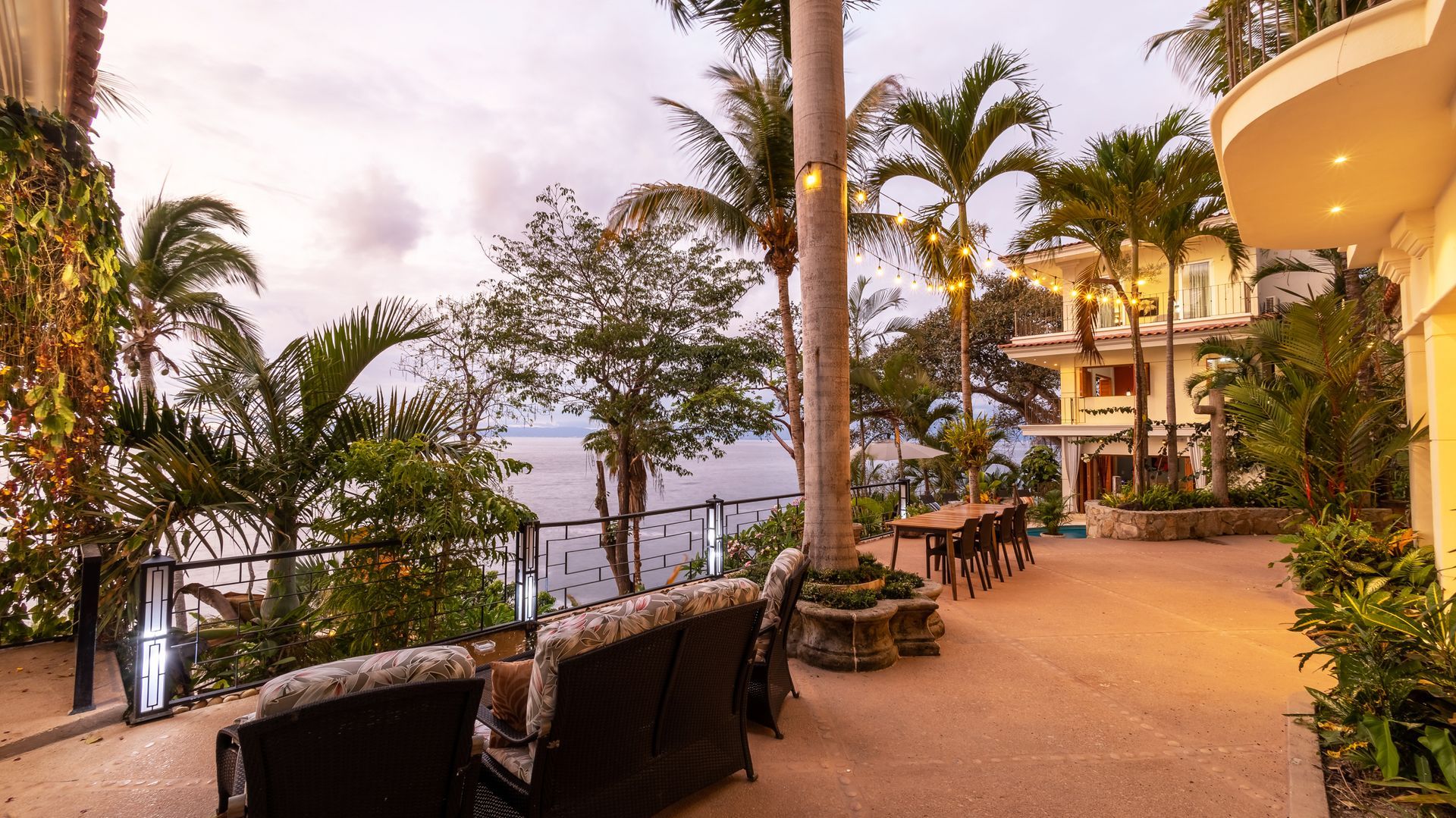 a large patio with a view of the ocean and palm trees
