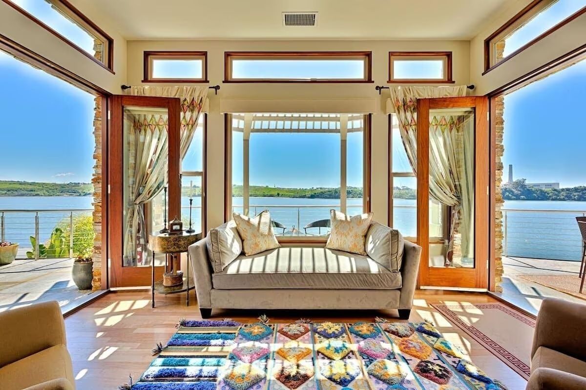 a living room with a couch and chairs and a view of the water