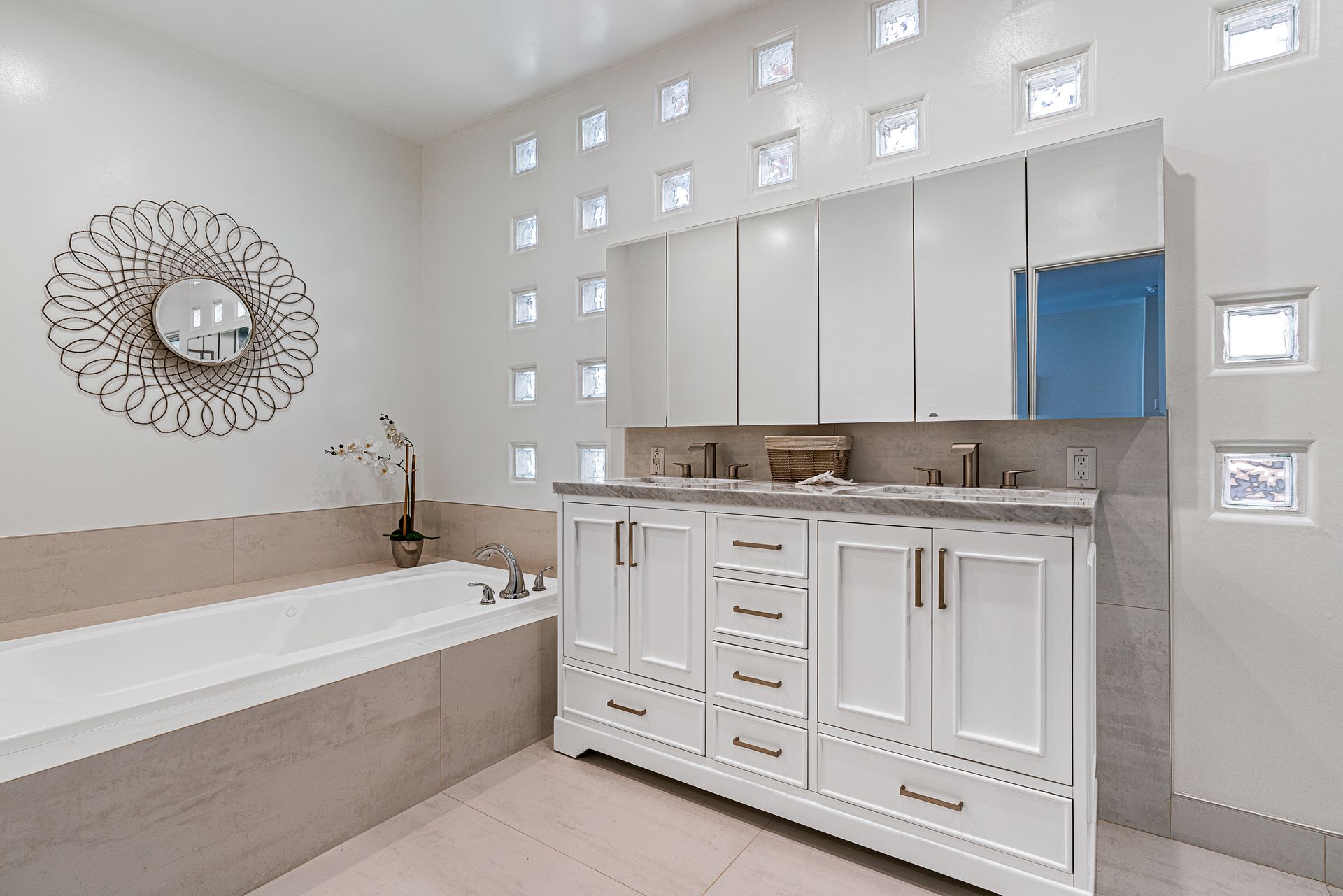 a bathroom with two sinks, two mirrors and wooden cabinets