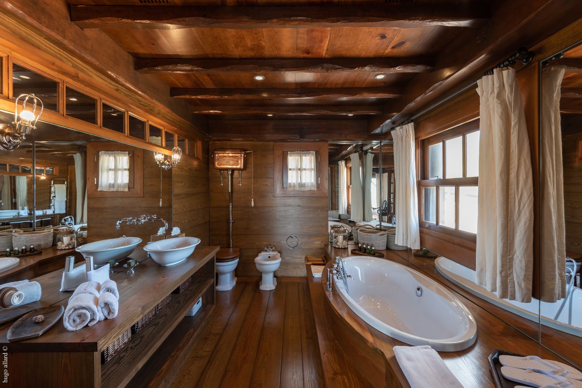 a bathroom with a bathtub, sinks, toilets and mirrors
