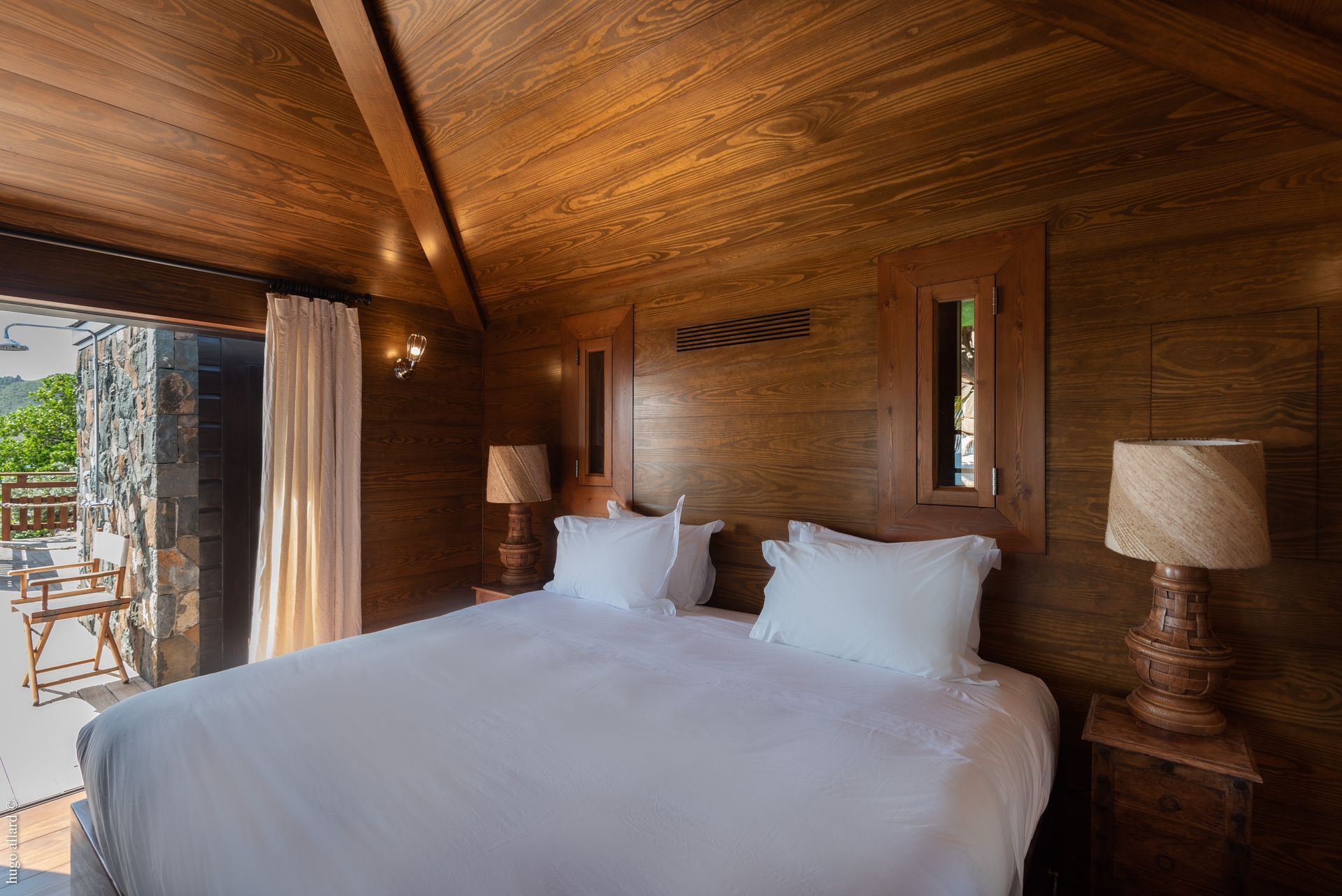 a bedroom with a bed, lamps, and a wooden ceiling