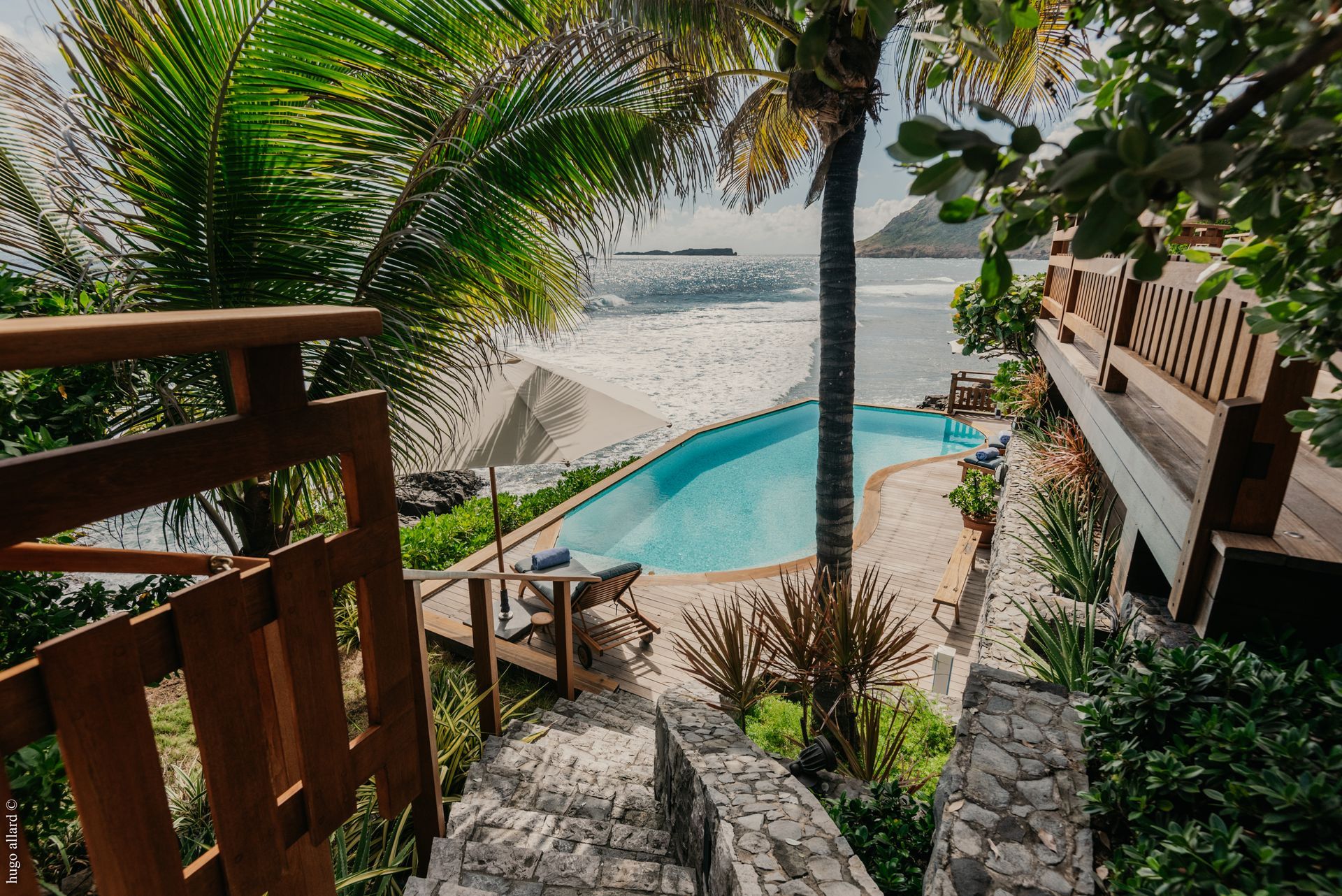 a swimming pool surrounded by palm trees and stairs leading to the ocean