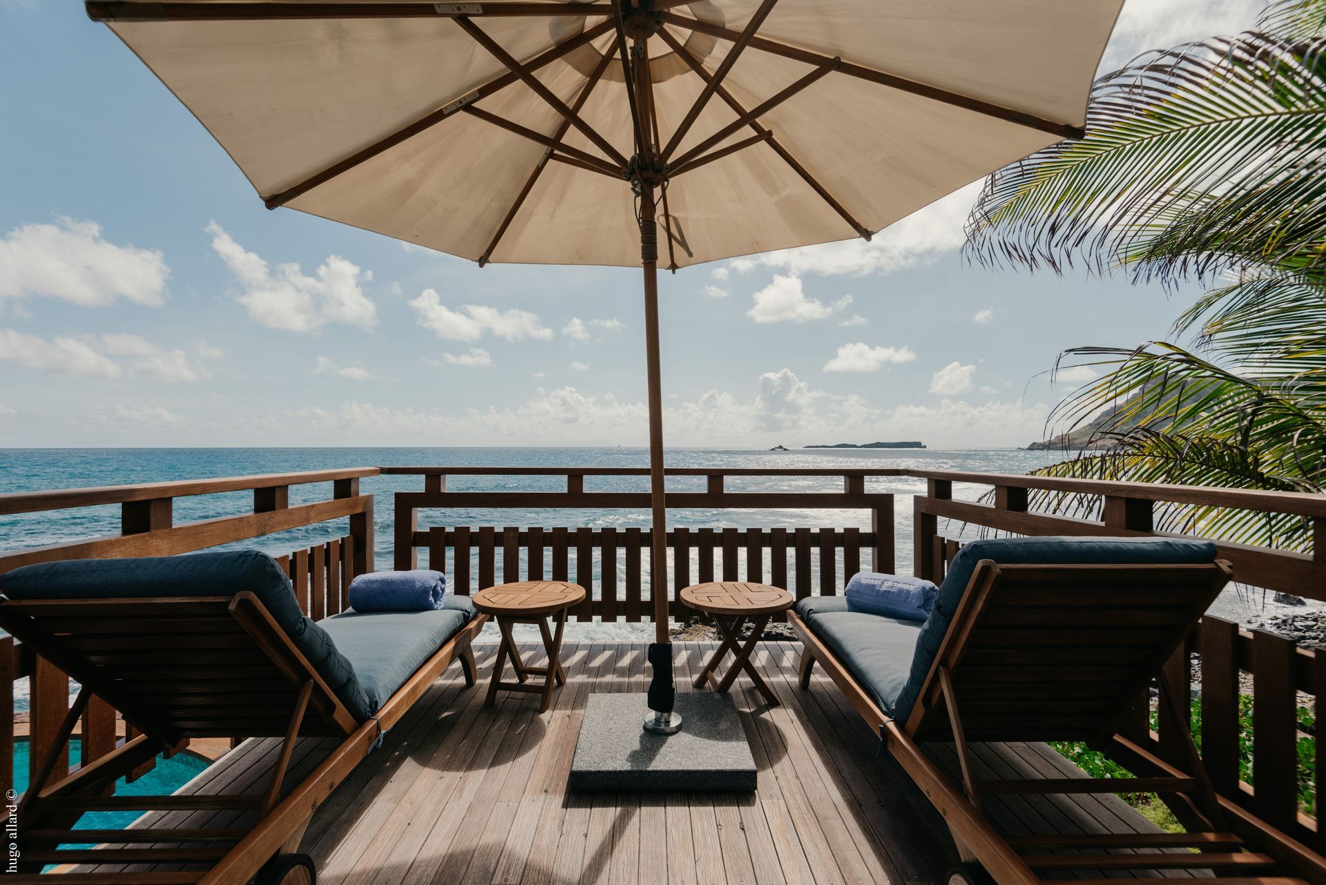 a balcony with chairs and an umbrella overlooking the ocean