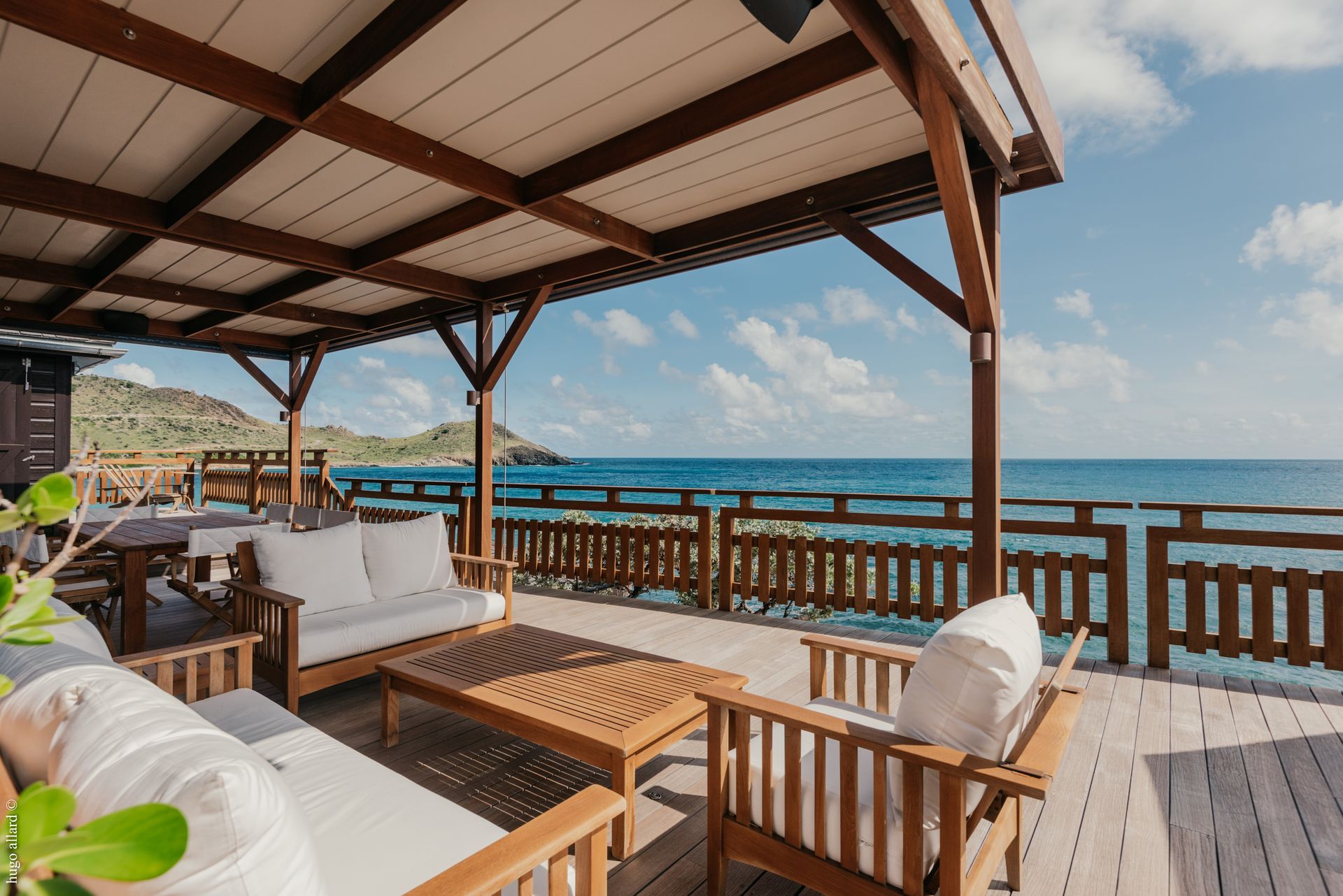 a wooden deck with a couch and chairs overlooking the ocean