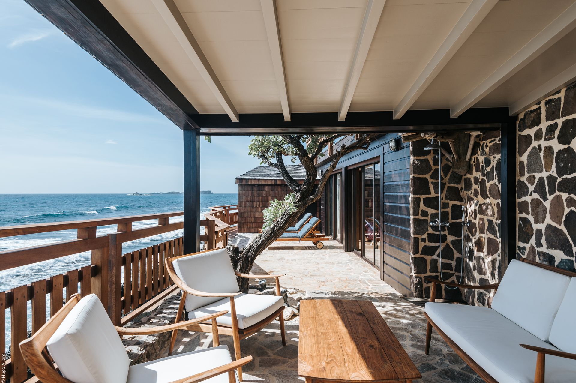 a patio with a couch, chairs and a table overlooking the ocean