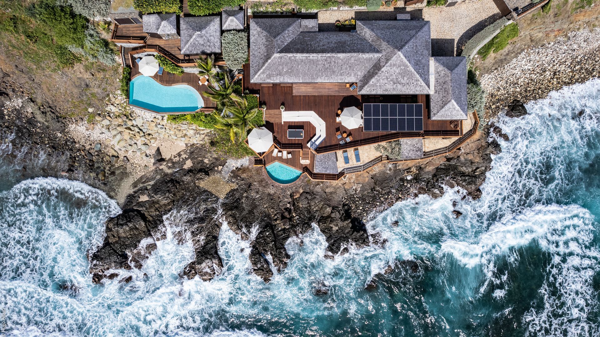 an aerial view of a house on a cliff overlooking the ocean