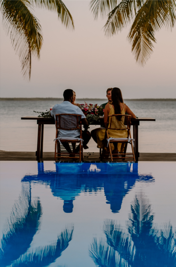 a man and a woman are sitting at a table by the ocean
