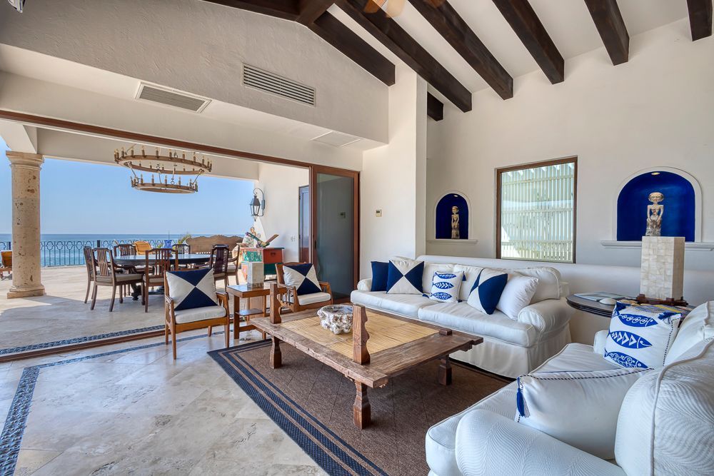 a living room with a couch, chairs, and a table with a view of the ocean