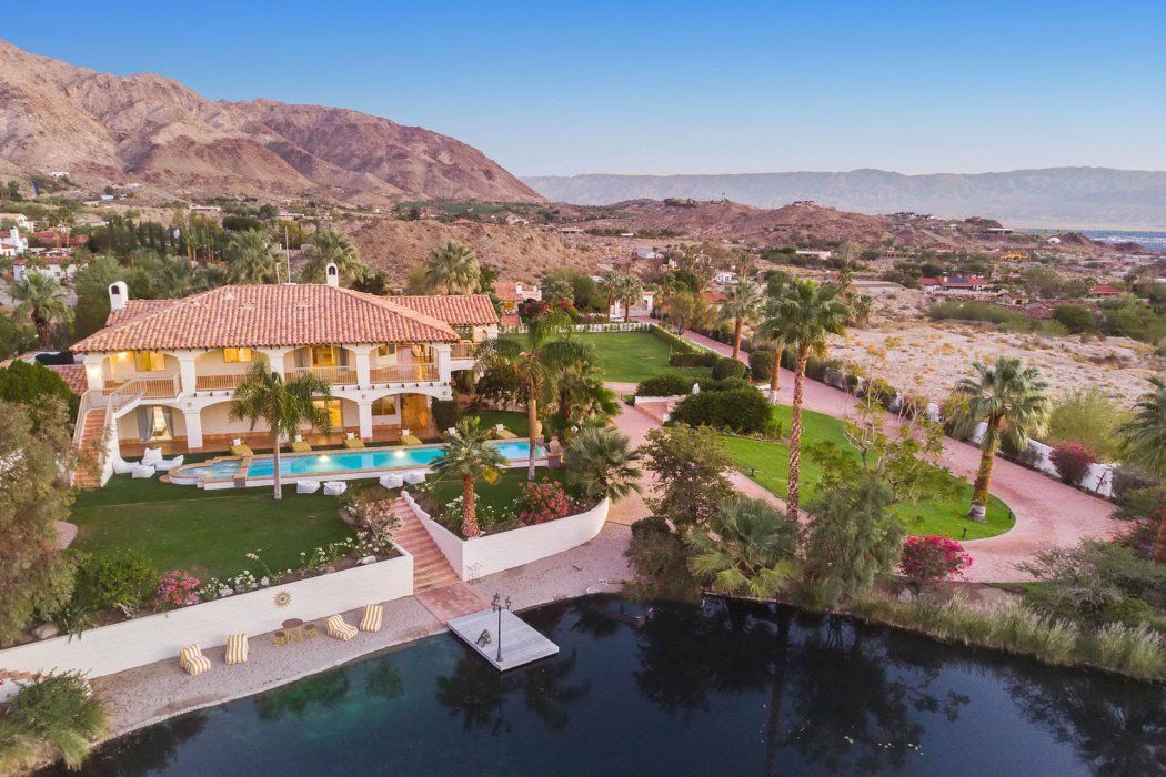 an aerial view of a large house with a large pond in front of it