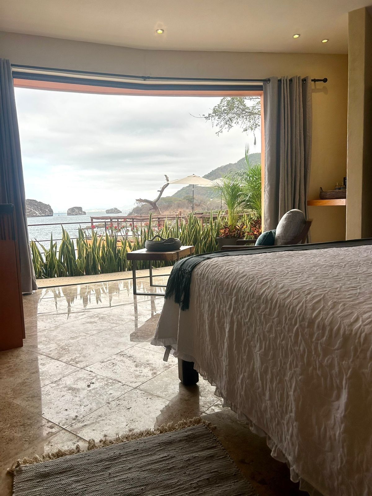 a bedroom with a bed and a large window with a view of the ocean