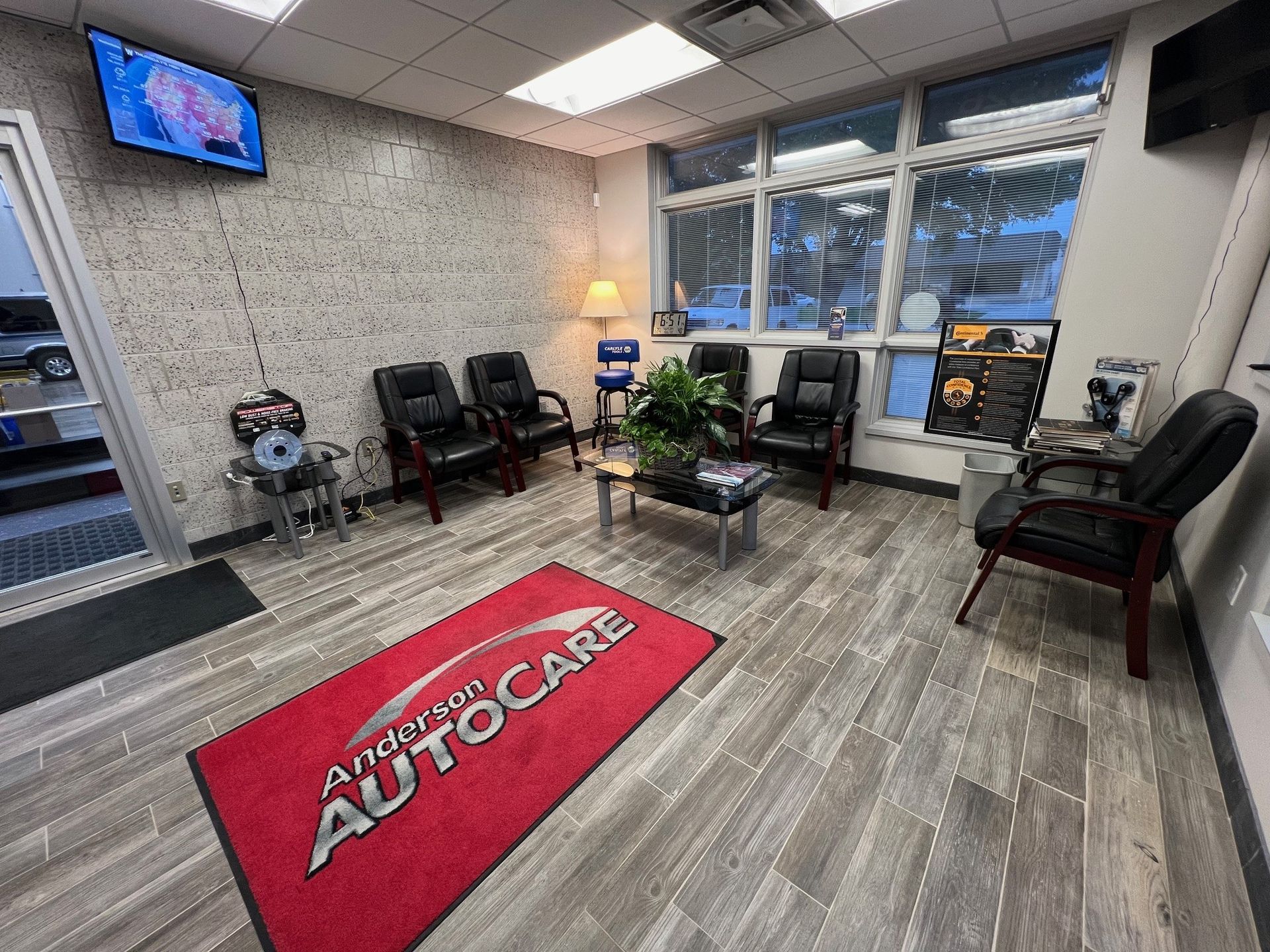 Waiting area at Anderson Autocare with seating, a welcome mat, and a television.
