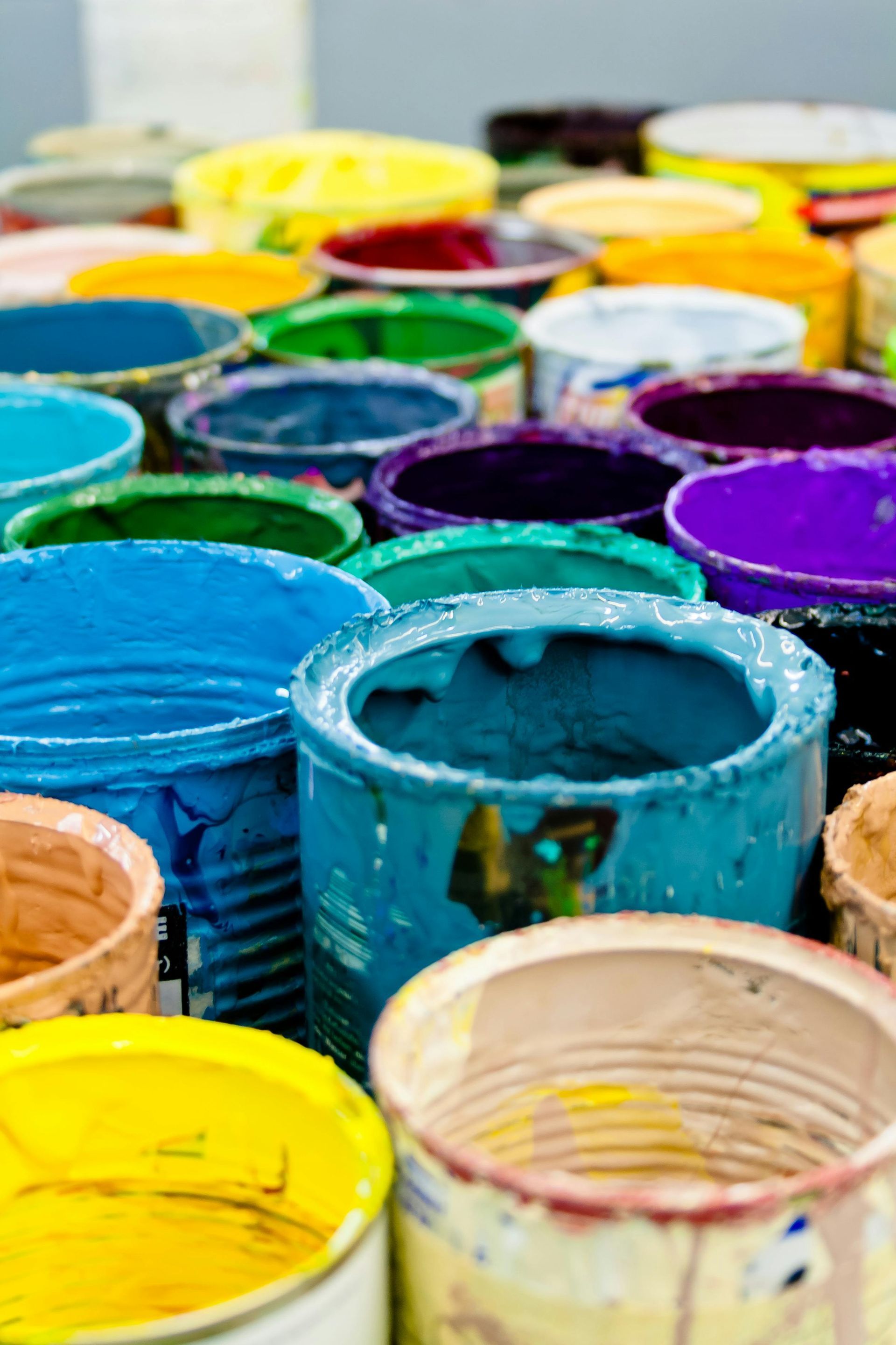 A bunch of buckets filled with different colors of paint.