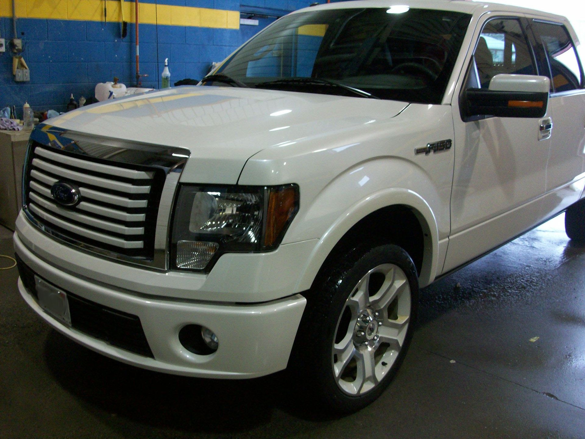 A white ford truck is parked in a garage