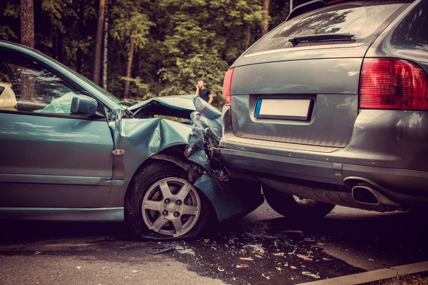 Two cars, one blue and one gray, after a car accident on a road.