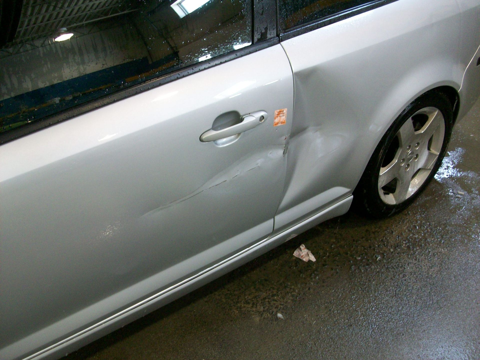 A silver car with a damaged side door