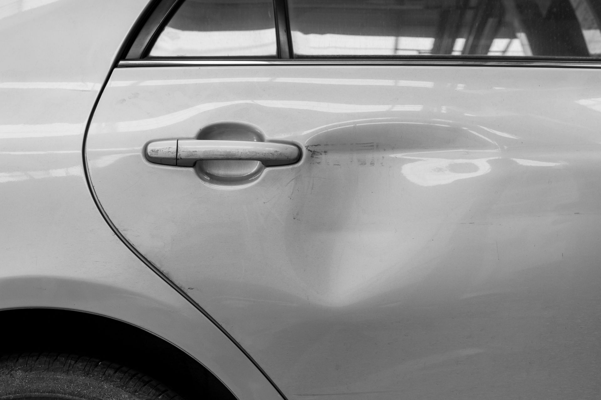 A close up of a car door with a dent in it.