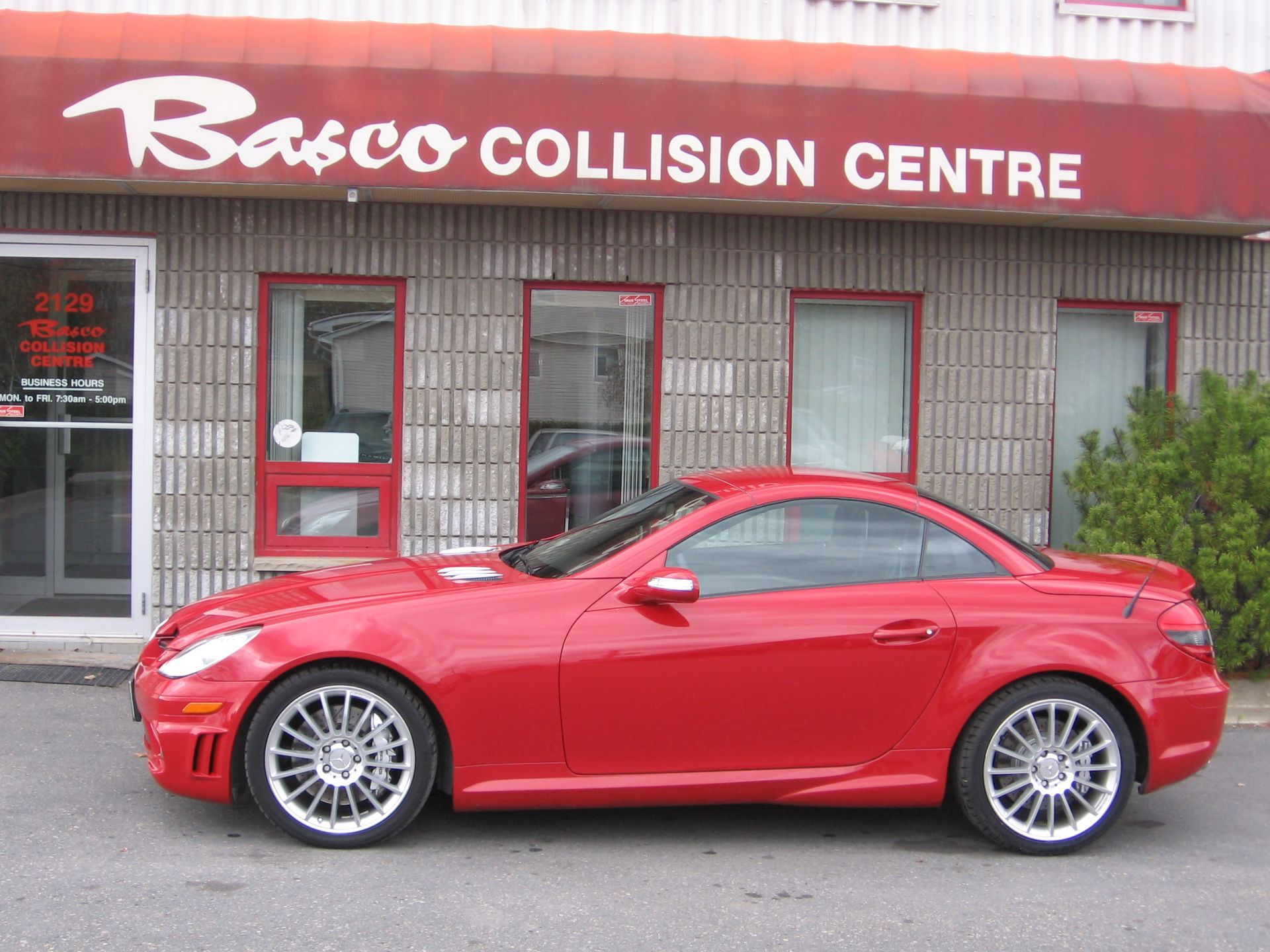 A red car is parked in front of the basco collision centre