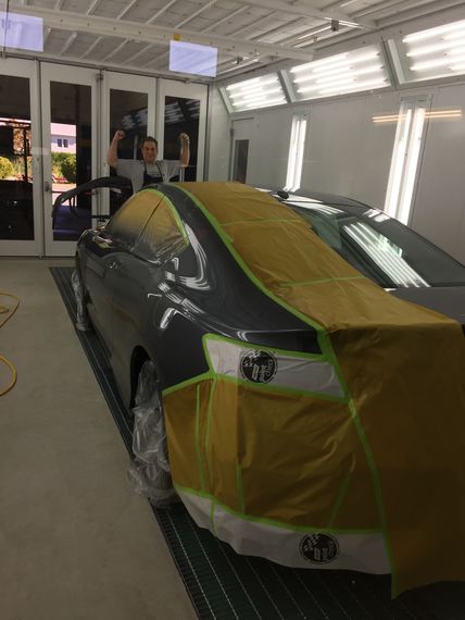 A car is being painted in a paint booth.