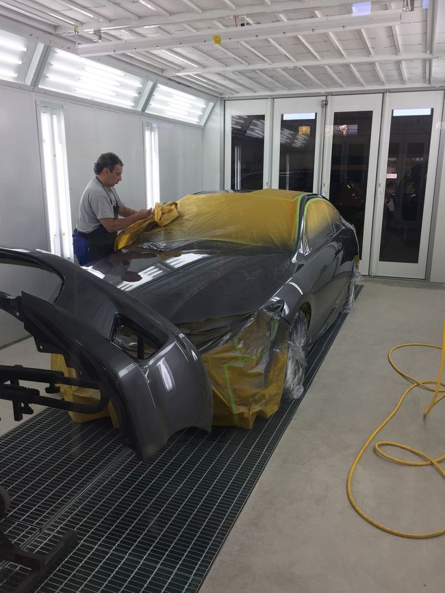 A man is painting a car in a paint booth.