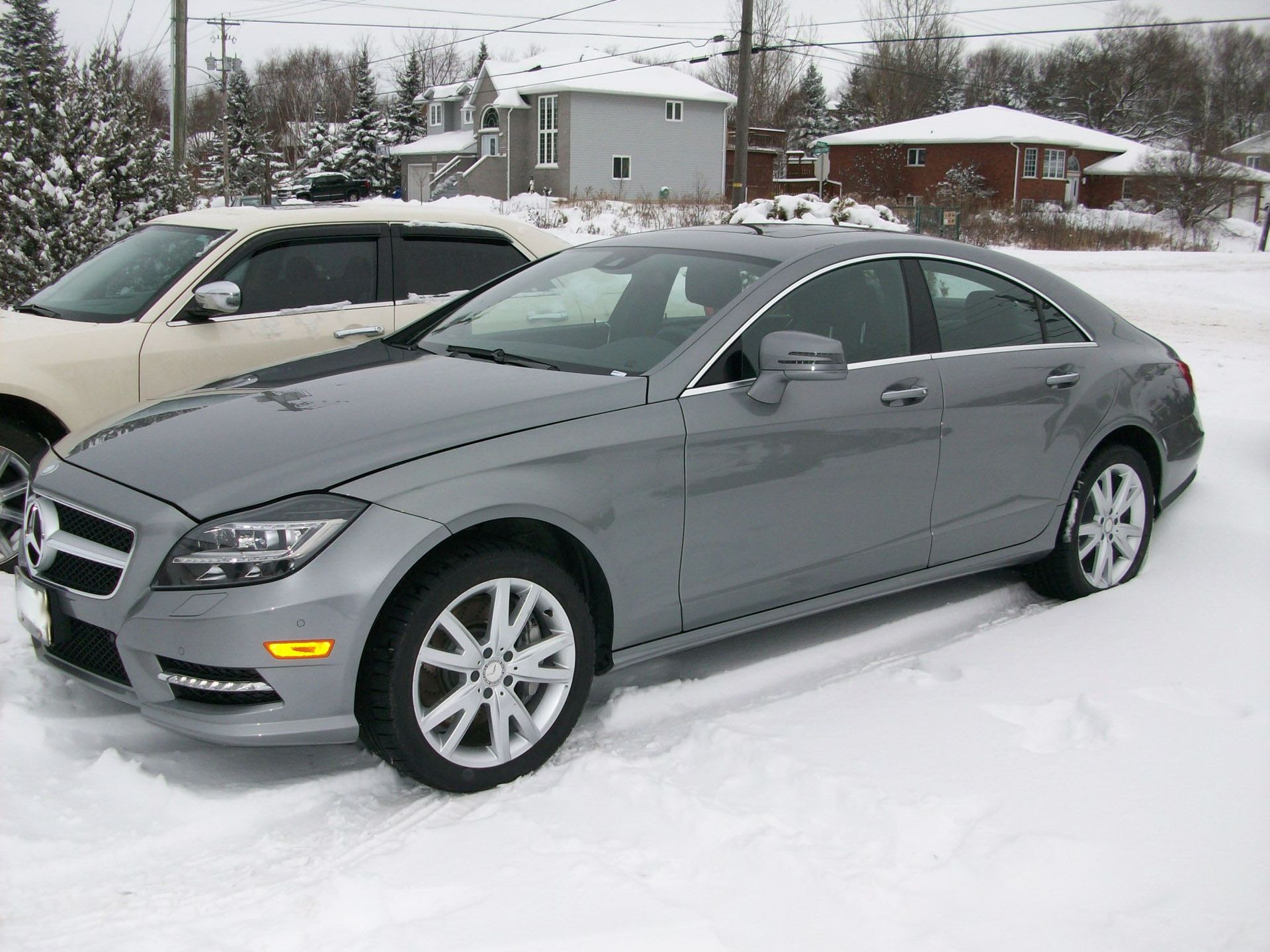 A silver mercedes benz is parked in the snow