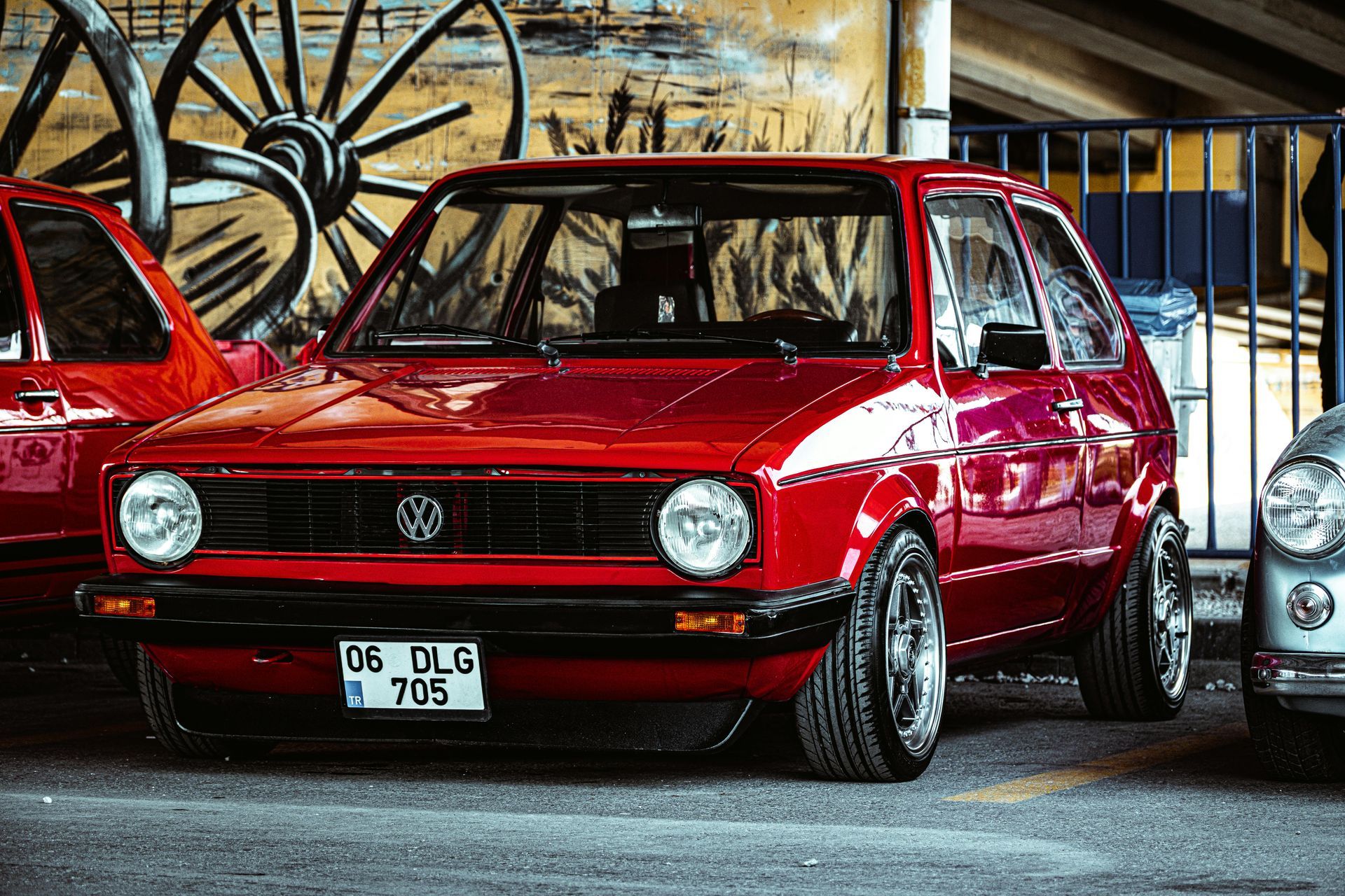 Red classic Volkswagen Golf parked in a garage, with chrome wheels and a custom lowered ride.