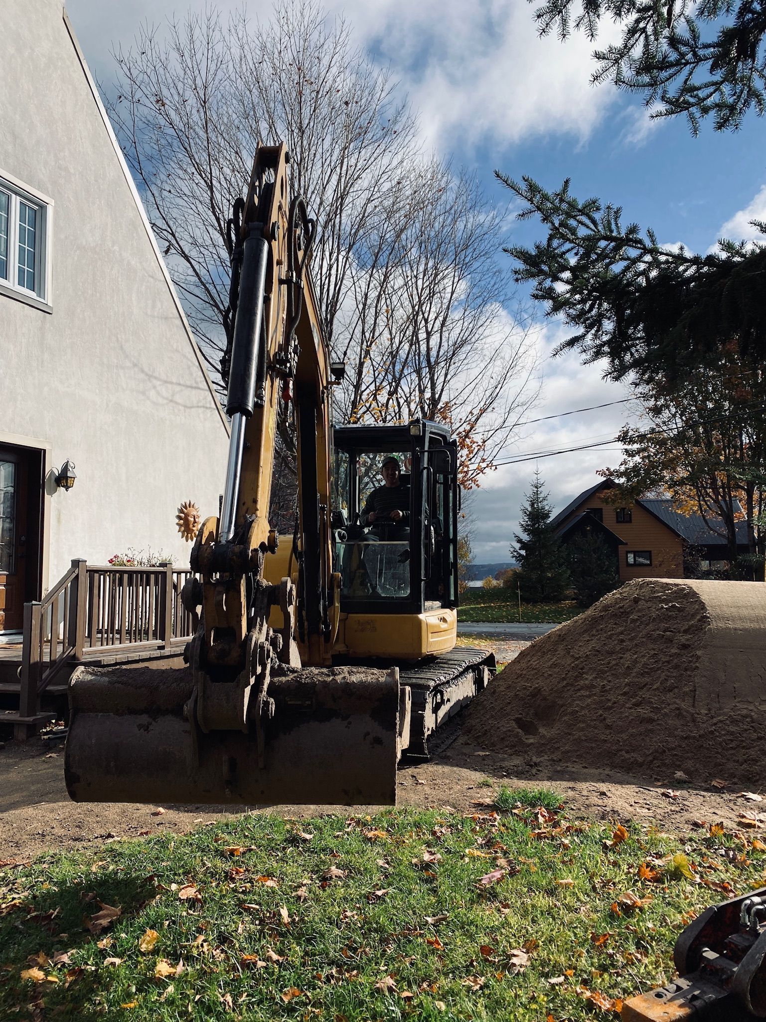 Une excavatrice déplace de la terre devant une maison