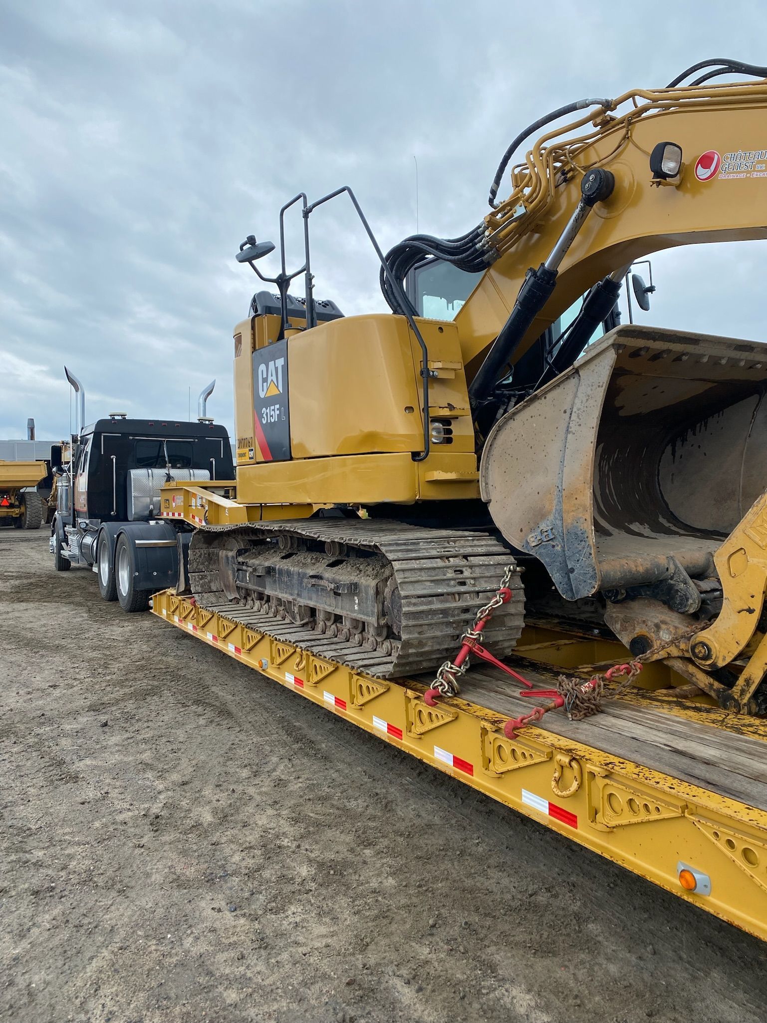 Une grande excavatrice est assise sur une remorque.