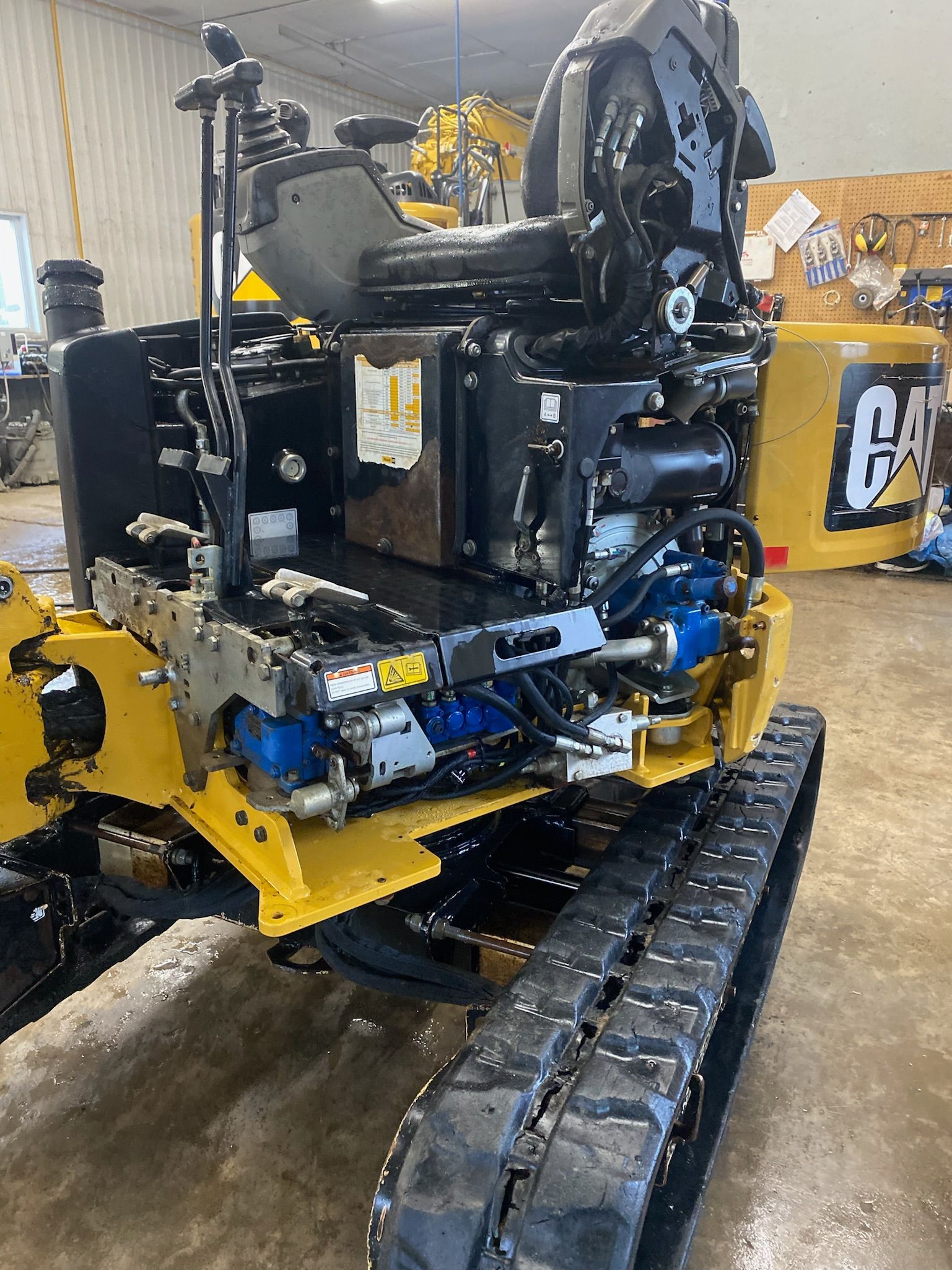 Un tracteur jaune et noir est assis sur un sol en béton dans un garage.