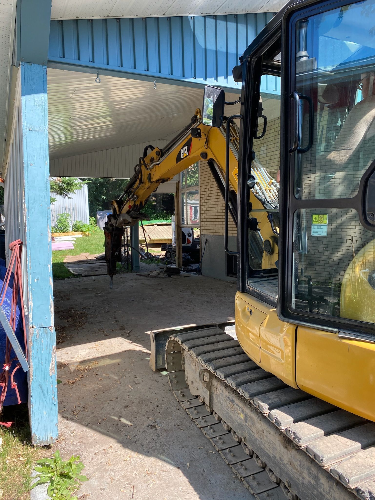 Une excavatrice jaune est garée devant un bâtiment.