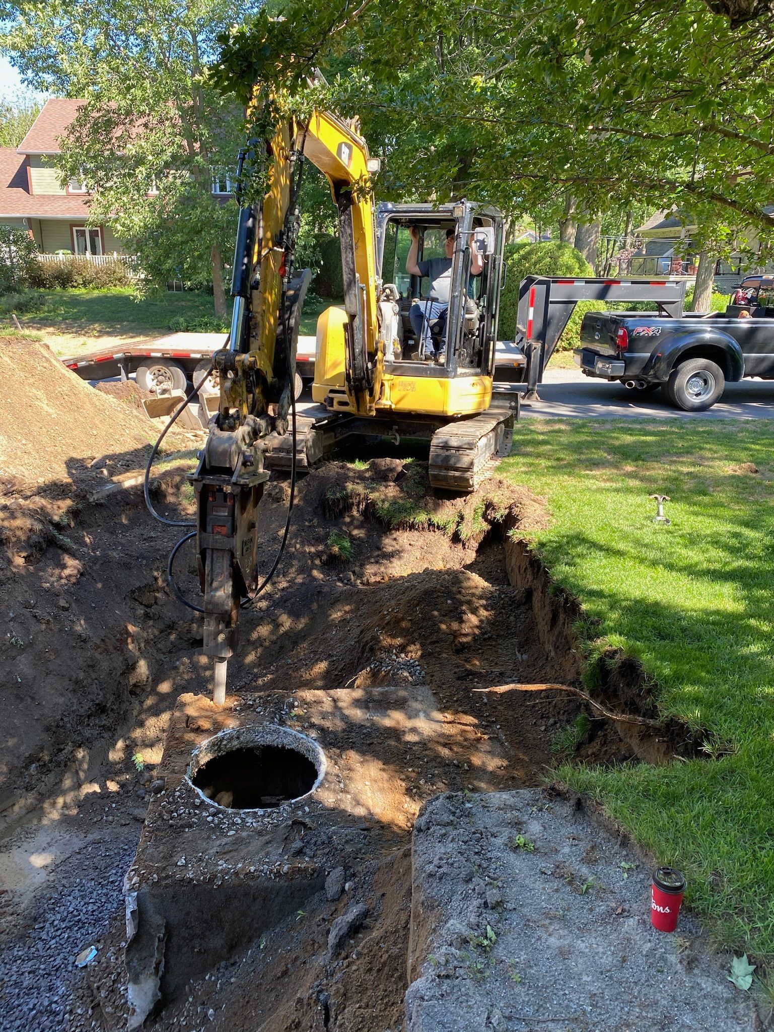 Une excavatrice jaune creuse un trou dans le sol dans une cour.