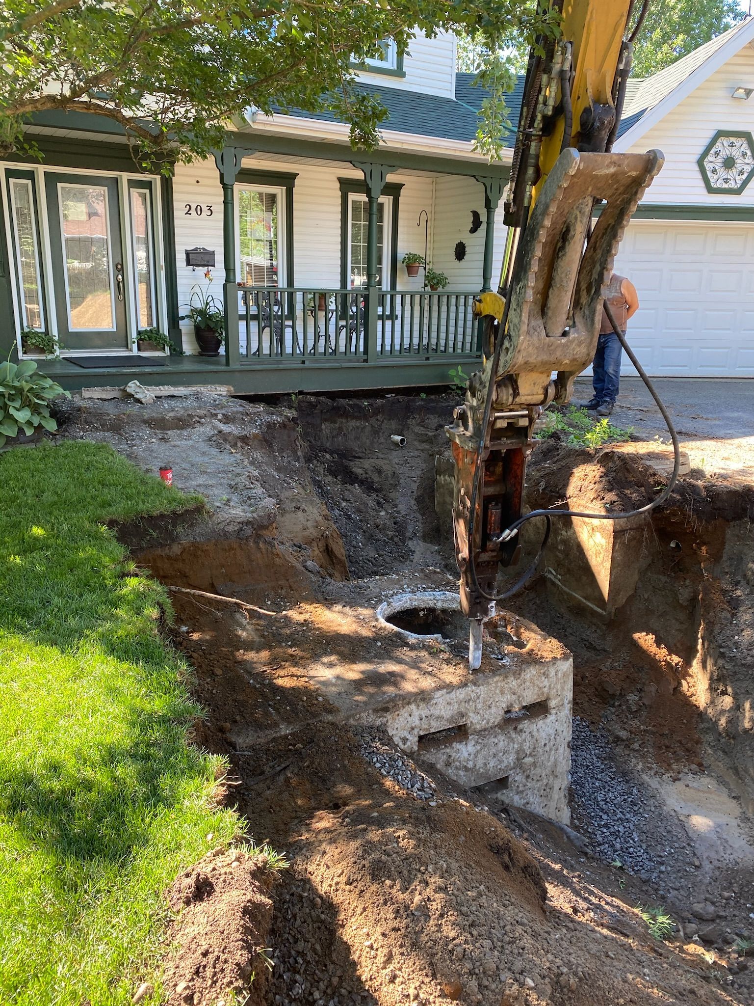 Un homme creuse un trou dans le sol devant une maison.