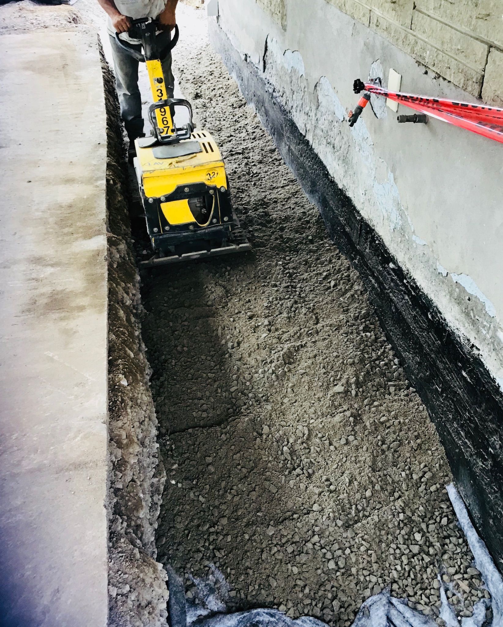 Un homme utilise une machine jaune pour compacter du béton.