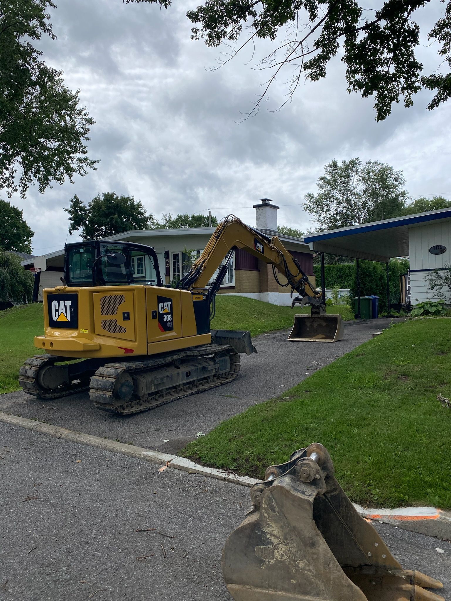 Une excavatrice jaune est garée devant une maison.