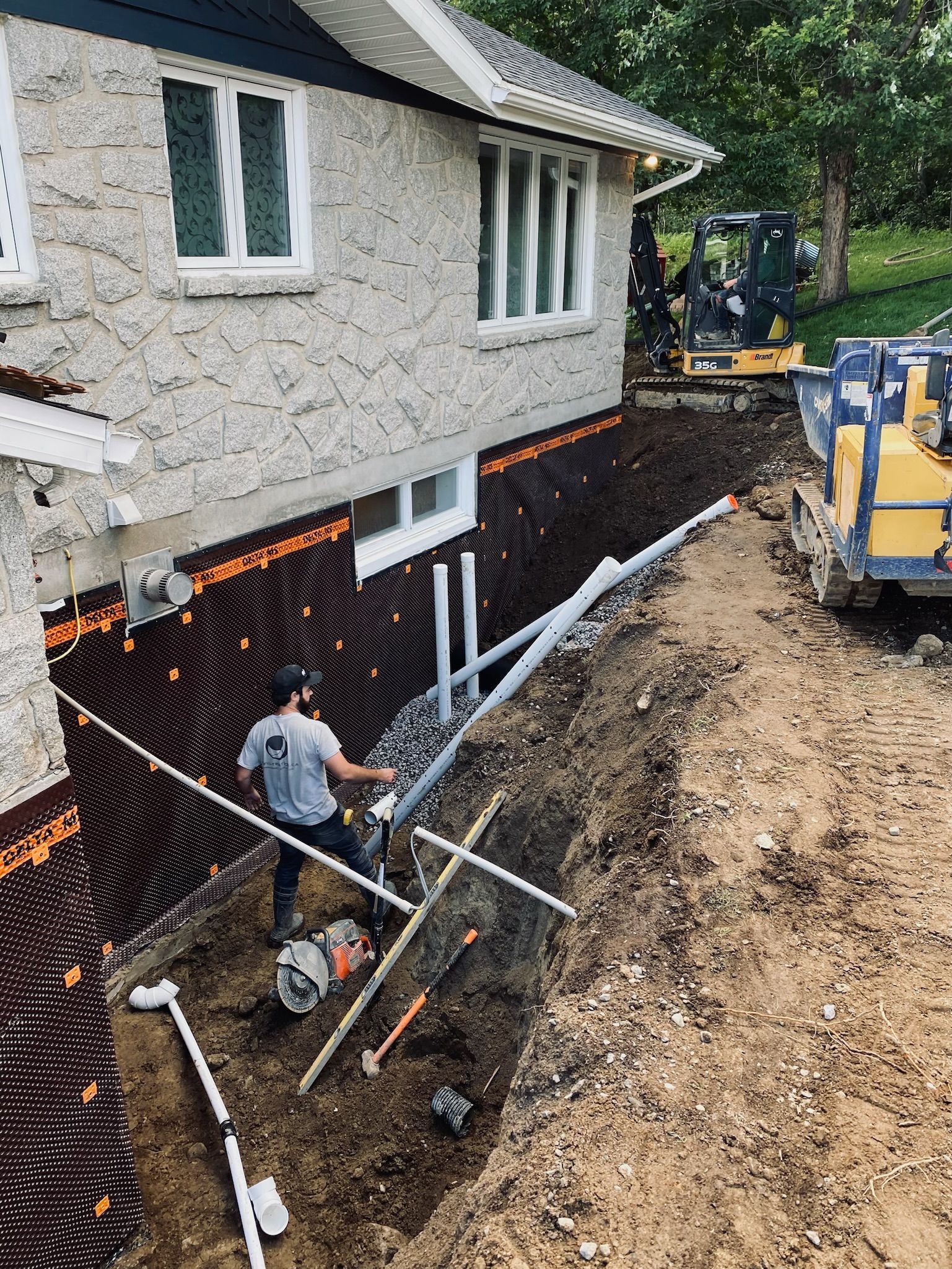 Un homme creuse un trou devant une maison.