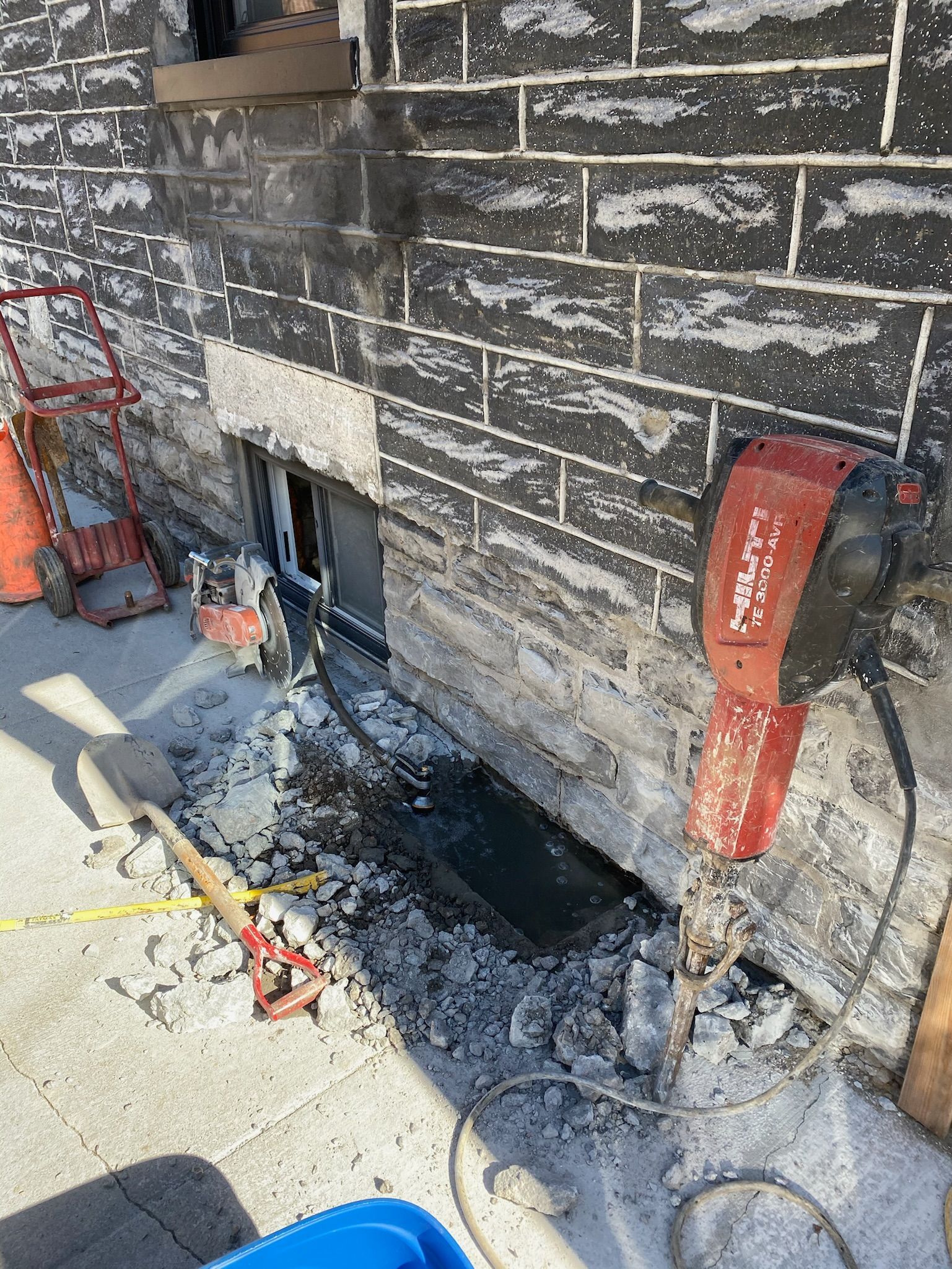 Une personne découpe un trou dans un mur de briques avec une machine.