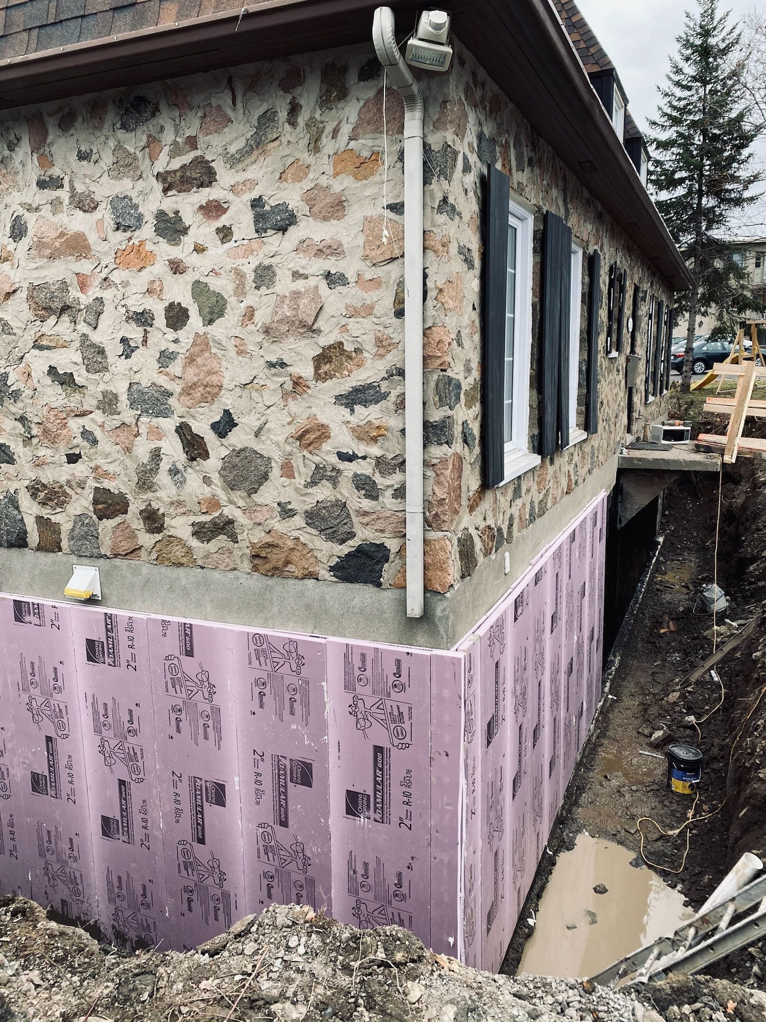 Une maison en pierre avec une isolation violette sur le côté.