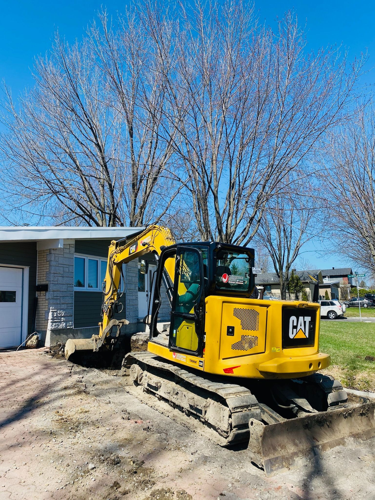 Une excavatrice jaune est garée devant une maison.