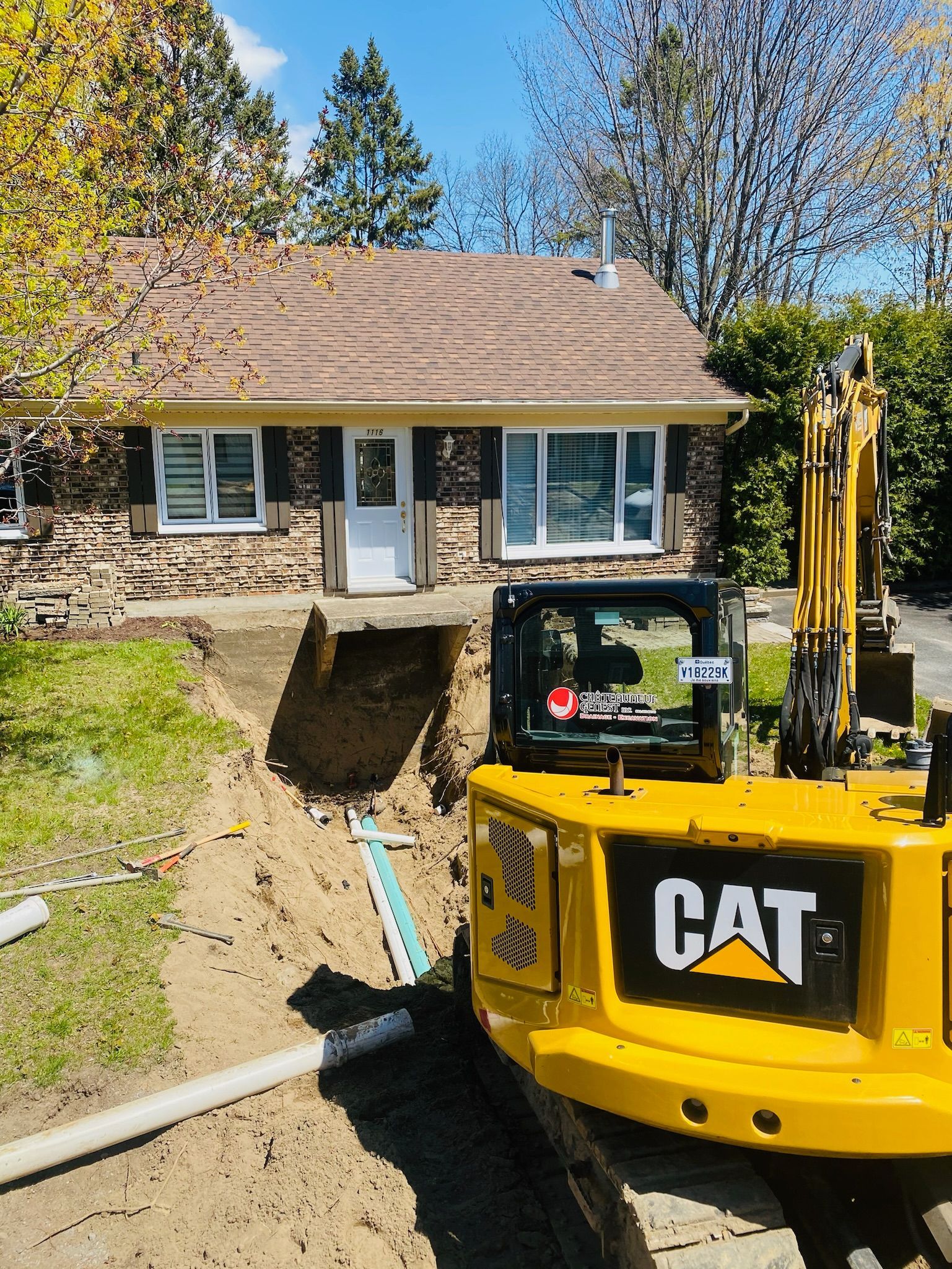 Une excavatrice jaune est garée devant une maison.