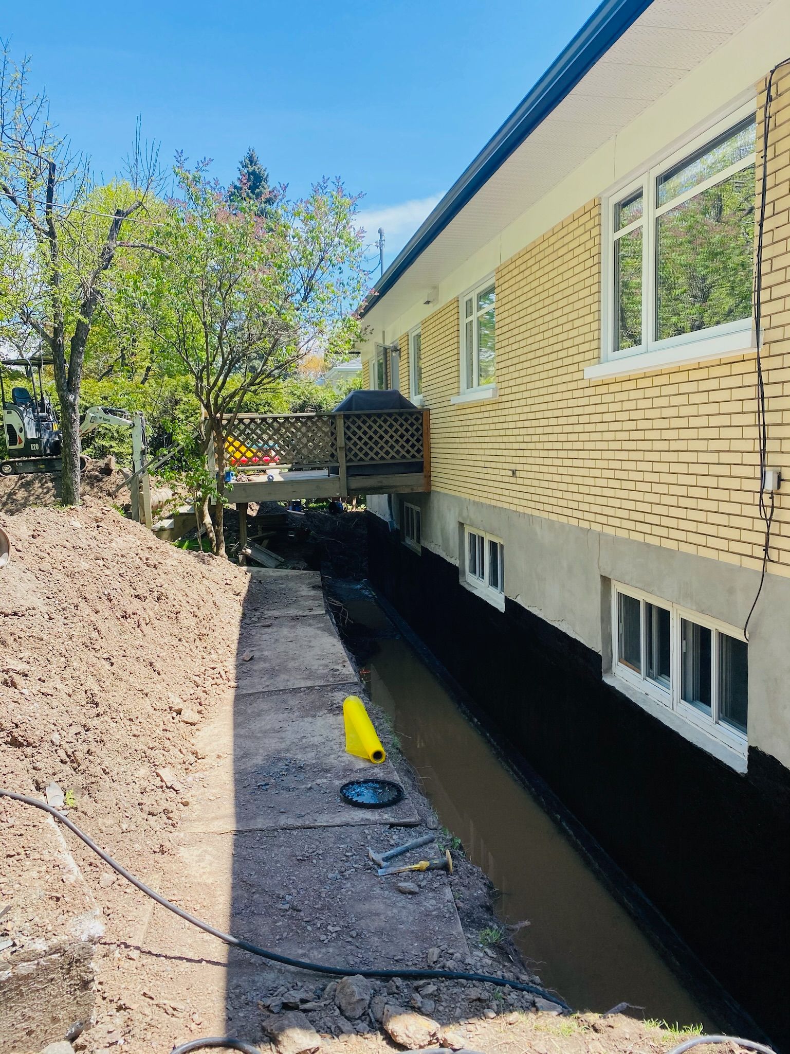 Une maison avec beaucoup de fenêtres est entourée d'arbres et de terre.