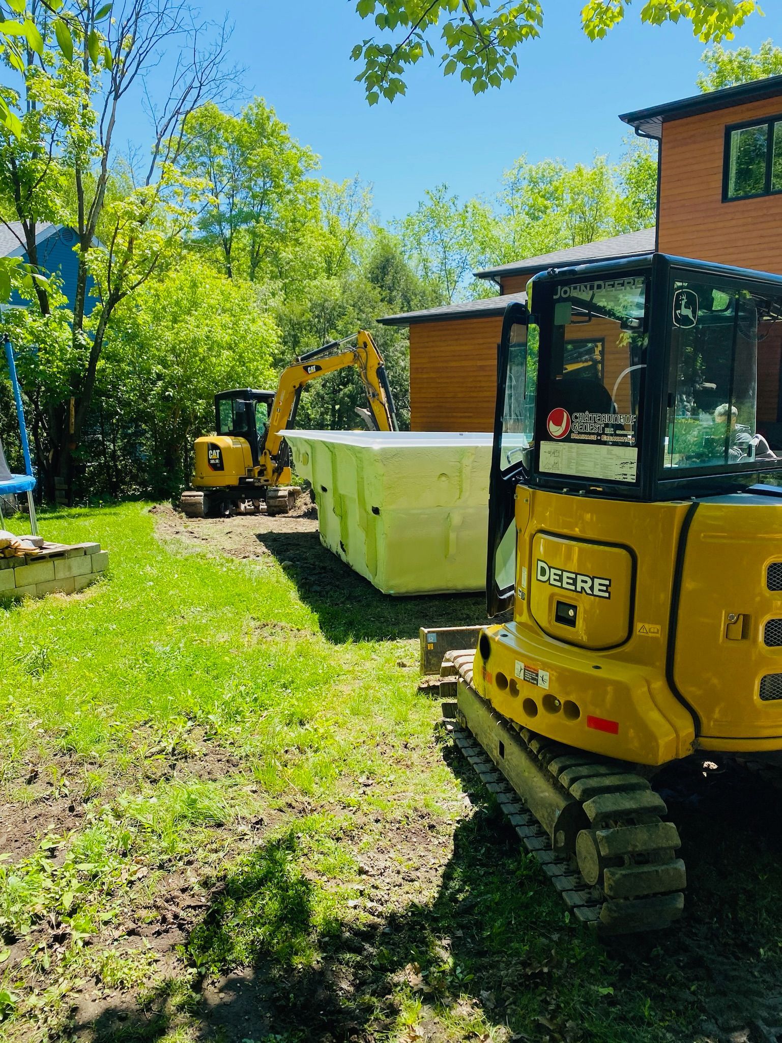Une excavatrice jaune est garée devant une maison.