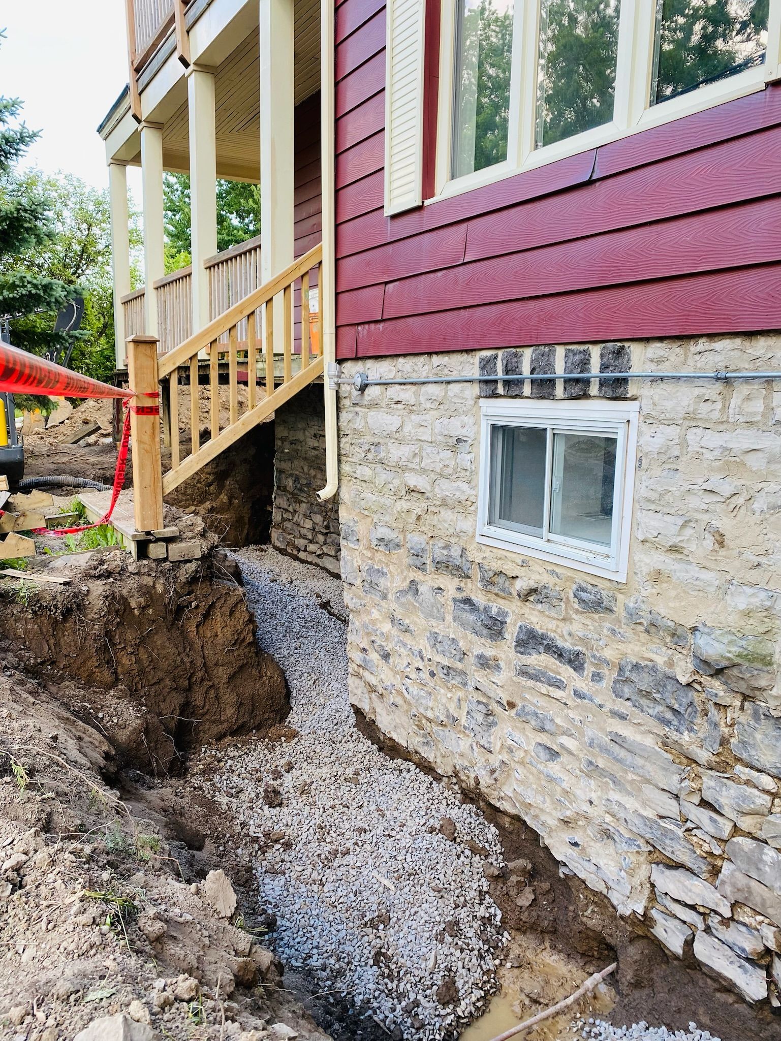 Une maison avec un bardage rouge et un mur en pierre est en cours de rénovation.