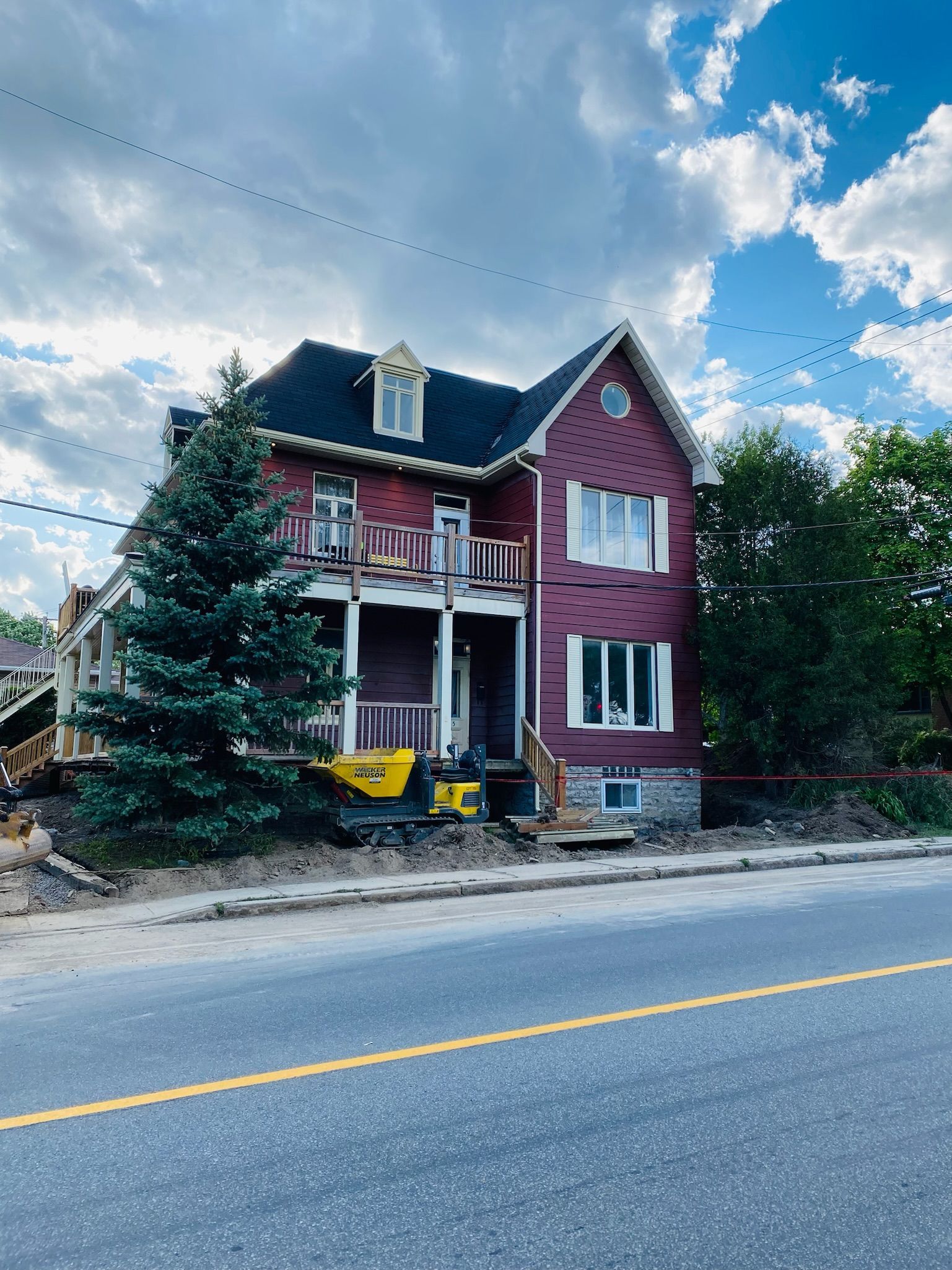 Une maison rouge avec un toit noir se trouve sur le bord de la route.