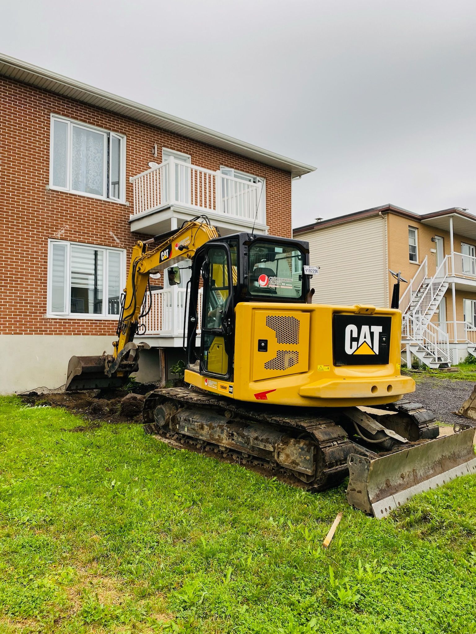 Un bulldozer jaune est garé devant une maison en briques.