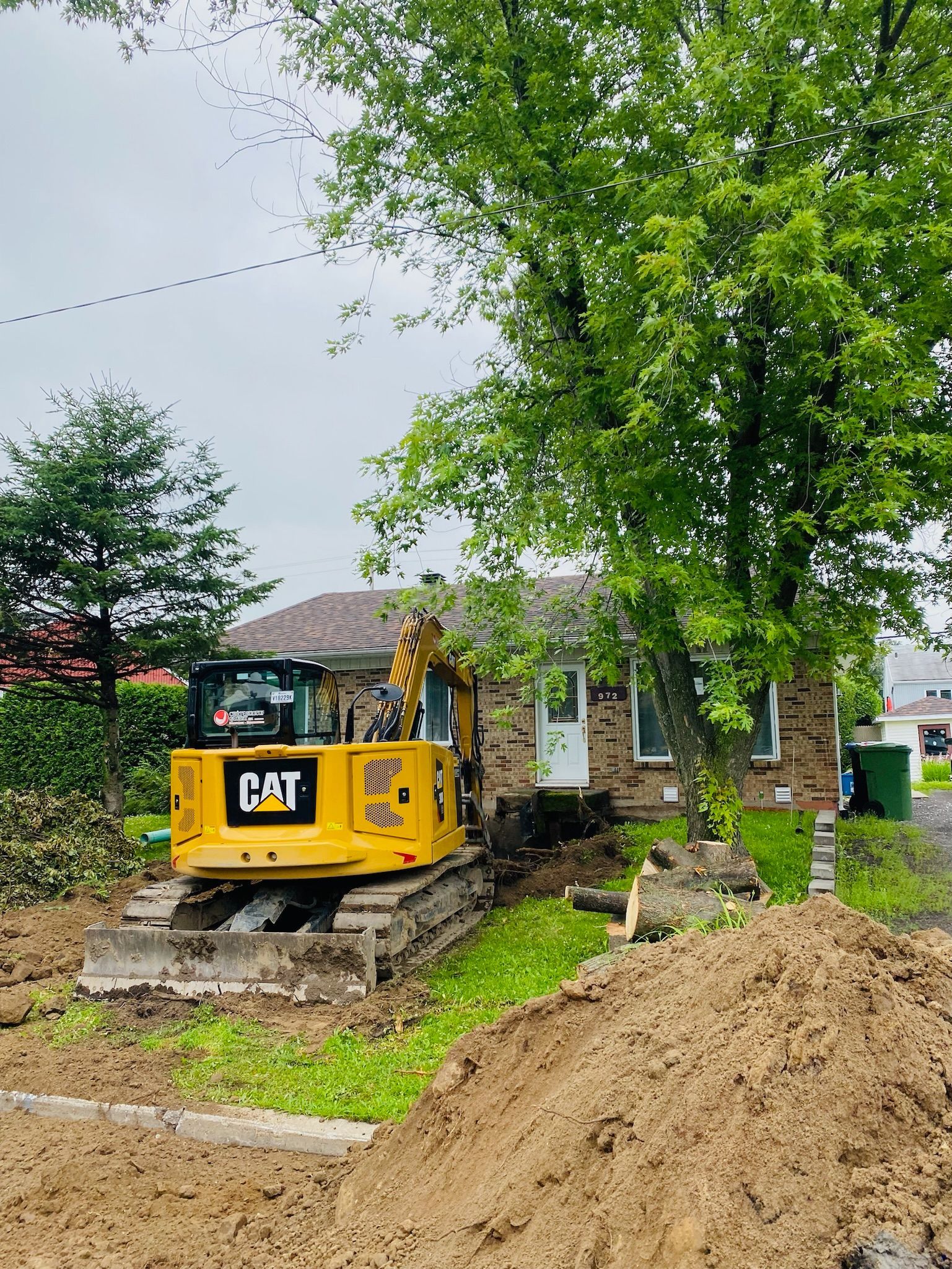 Une excavatrice jaune est assise devant une maison.