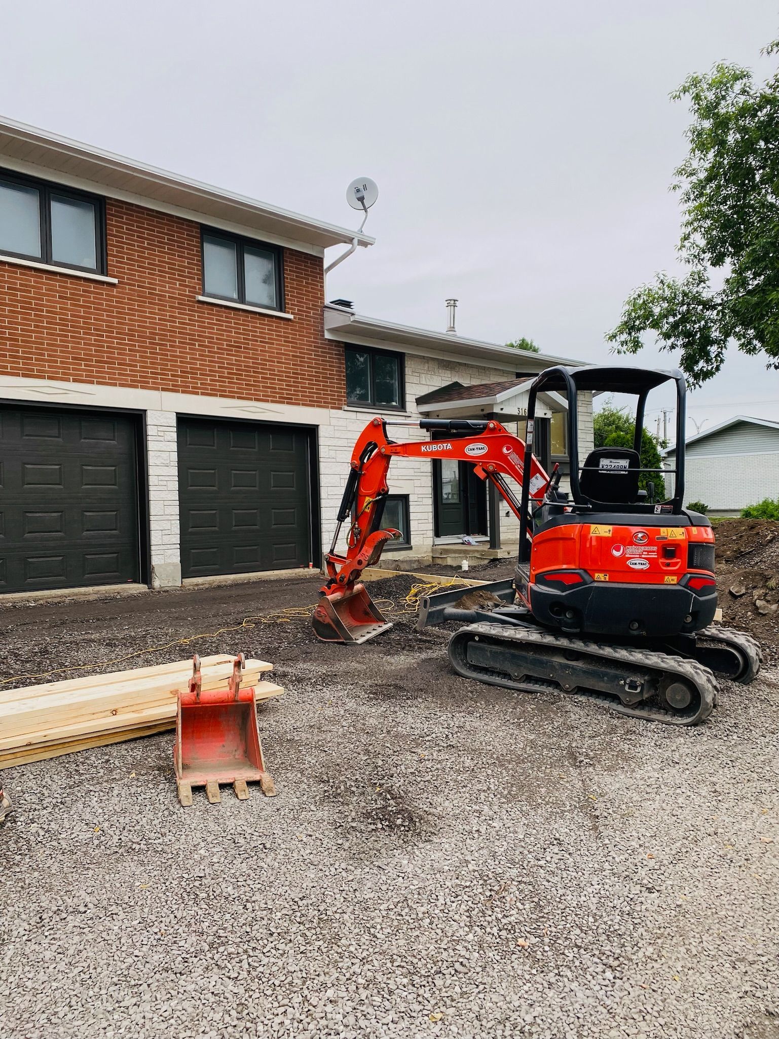 Une petite excavatrice est assise devant une maison en briques.